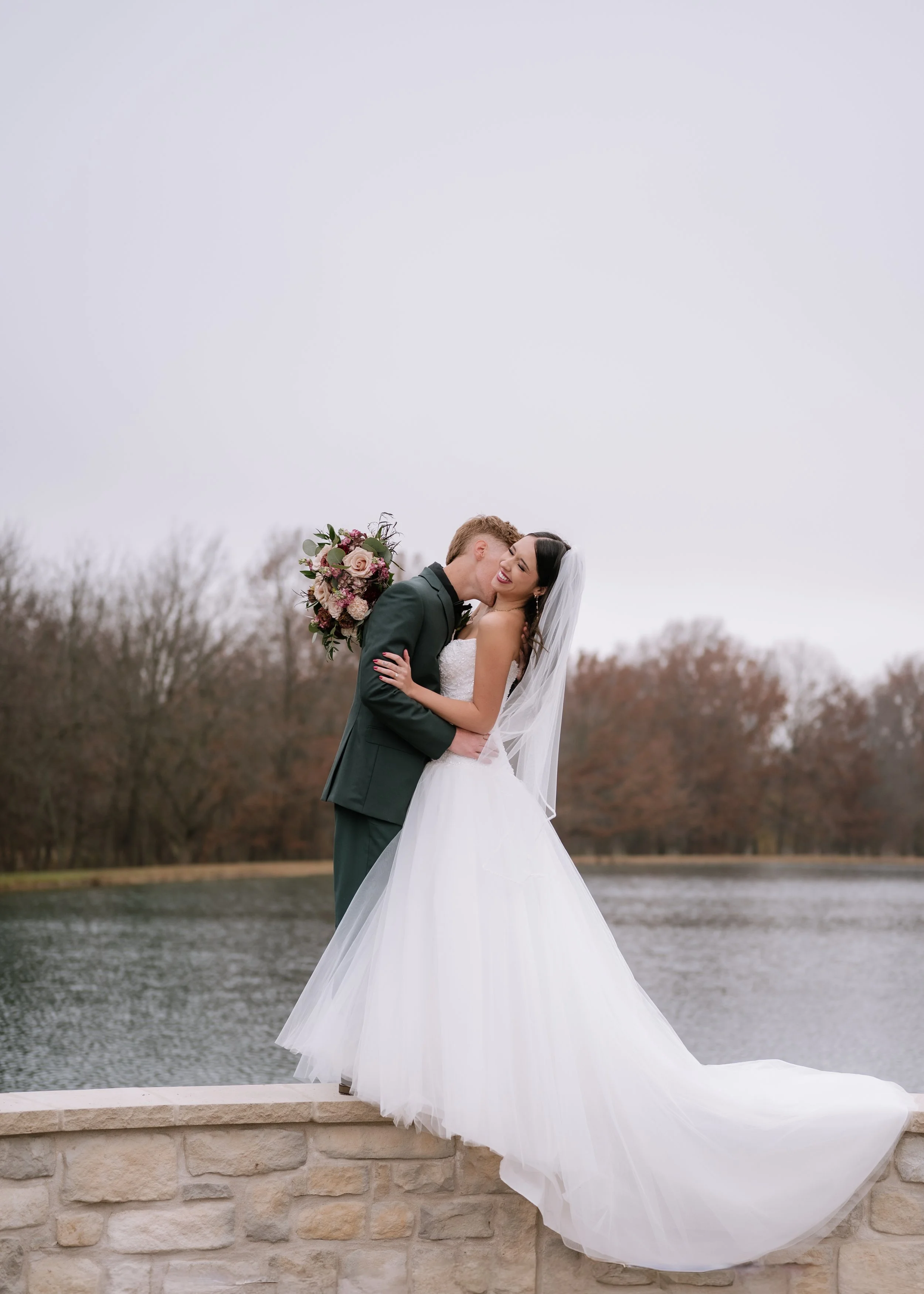 Bride and groom kissing by a lake on their wedding day. Kansas wedding. Kansas City wedding. Kansas City wedding photography. Missouri photographer. Missouri wedding. Missouri wedding photographer. Pittsburg KS wedding.