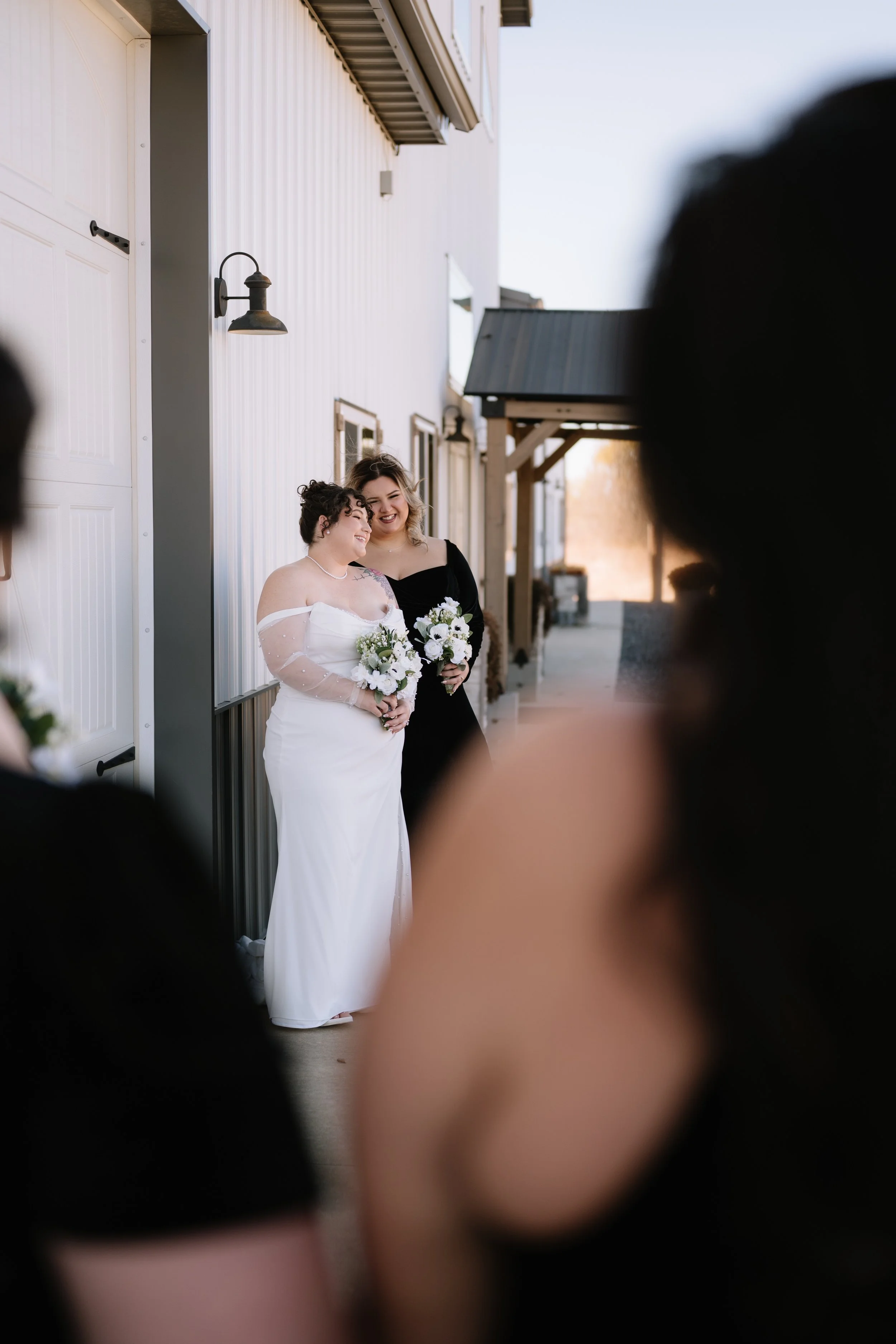 A bride and groom kiss during their wedding reception, holding champagne glasses, with a wedding cake nearby.
