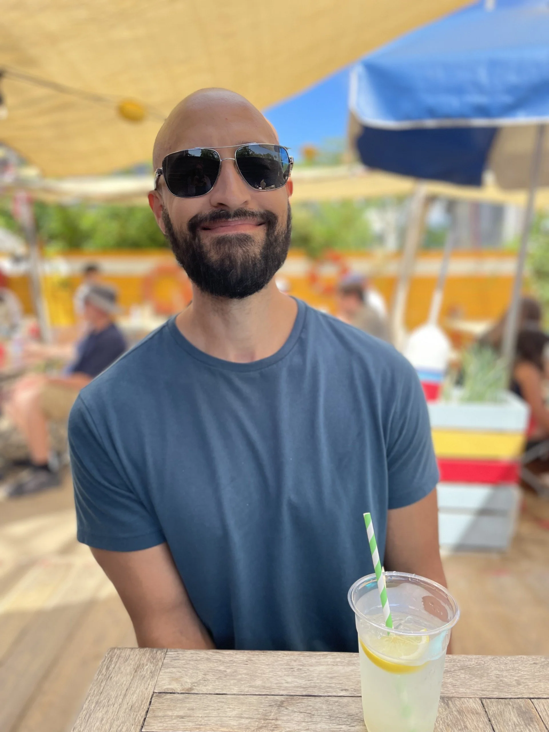 Man wearing sunglasses sits outside drinking lemonade