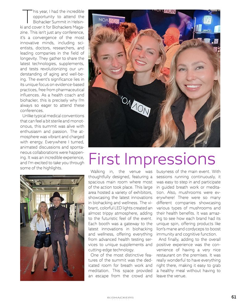 Three women smiling at a conference called Biohacker Summit in Helsinki, with a colorful LED-lit background and an exhibitor booth.