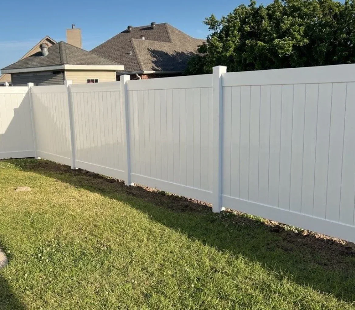Low-maintenance vinyl fence installed along with a shrub bed.