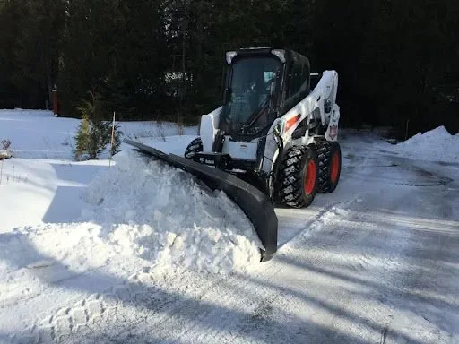 A skid steer loader clearing snow from a road or driveway.