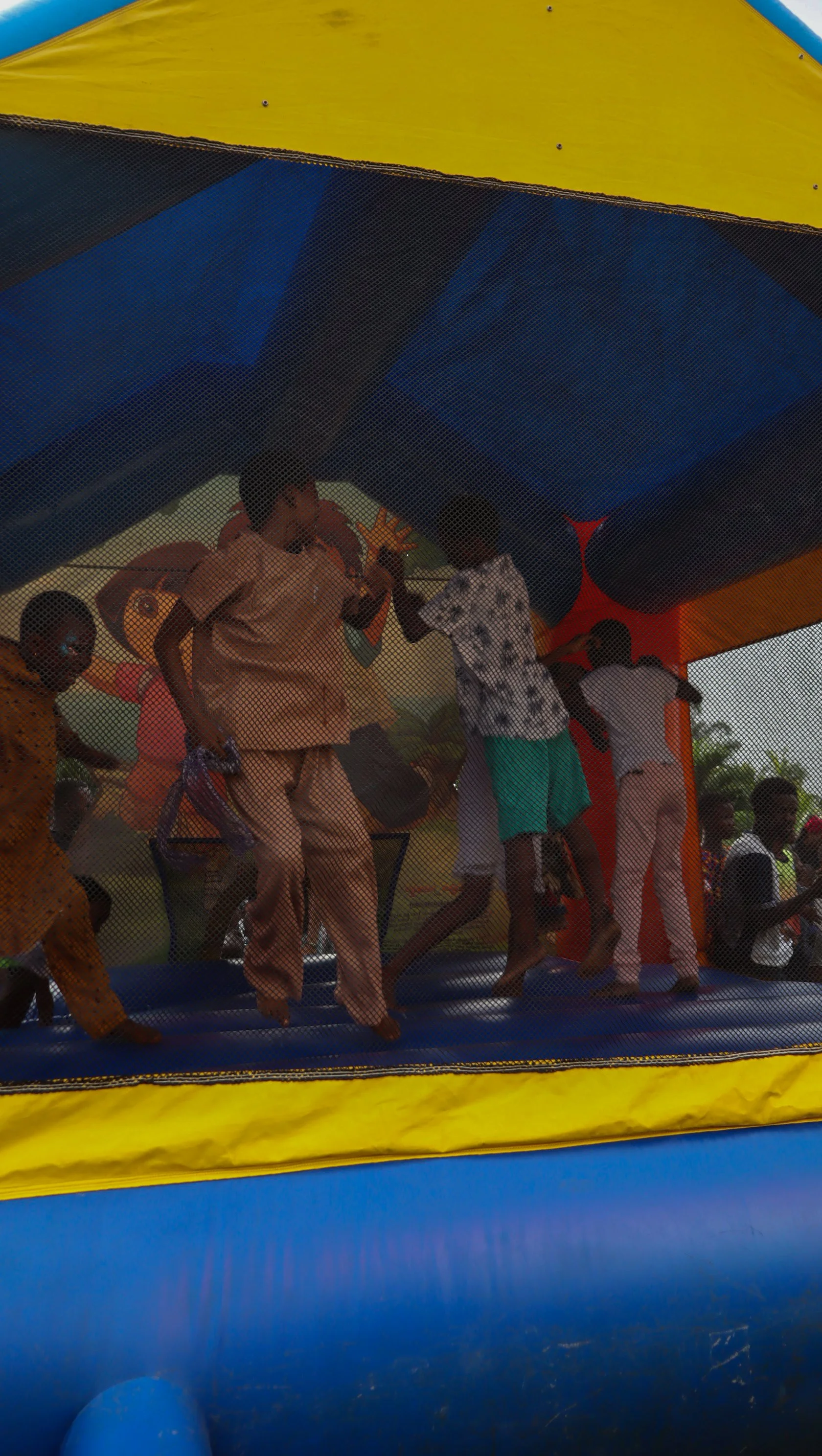 Children playing inside a colorful bounce house or inflatable castle with mesh sides.