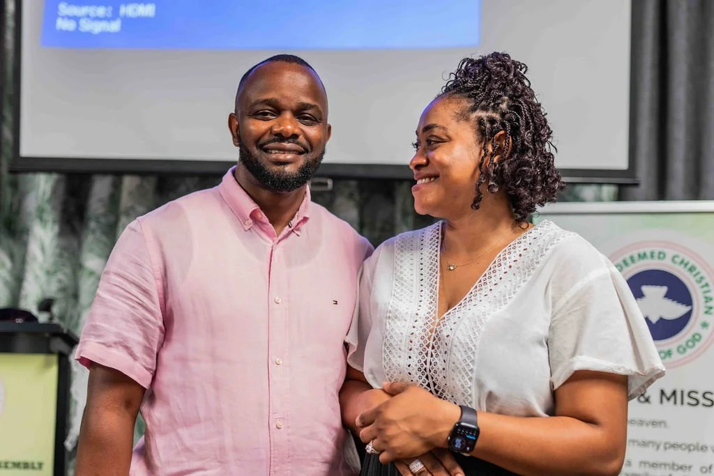 Smiling man and woman standing together at a Christian organization event in front of a presentation screen