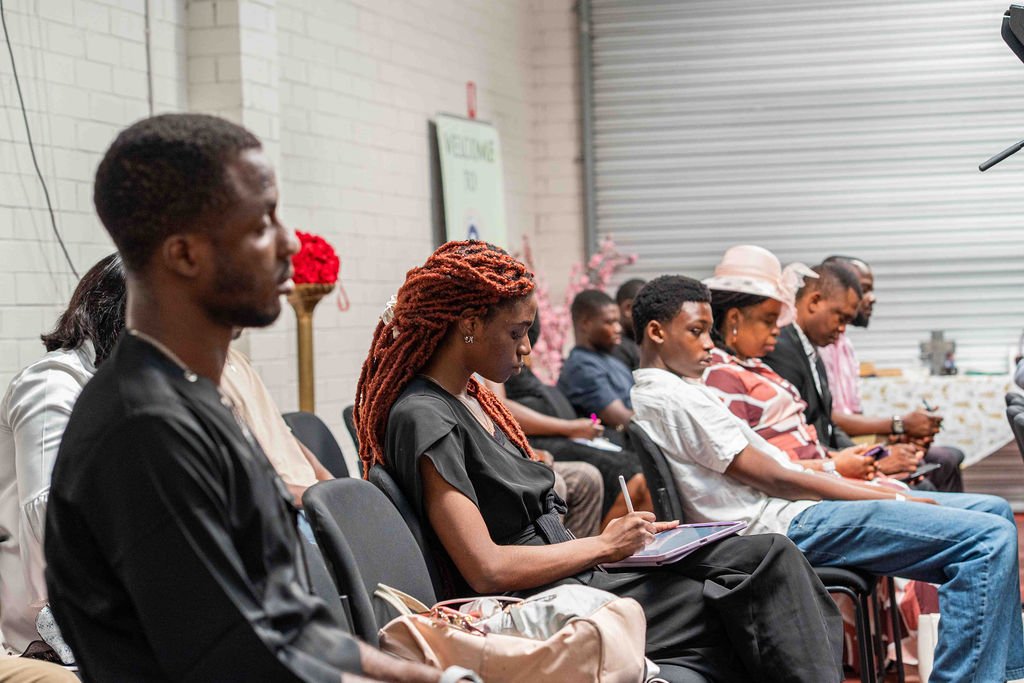 Diverse group of adults attending a workshop, seated in rows and taking notes.
