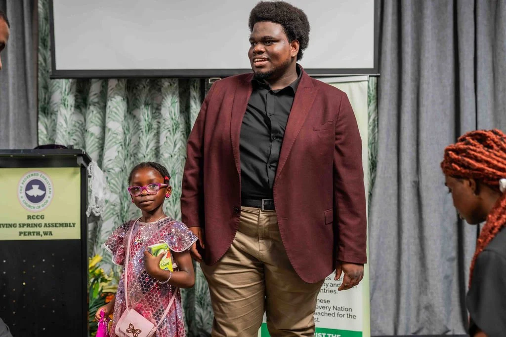Man in burgundy blazer standing with a young girl at a church event in Perth, Western Australia
