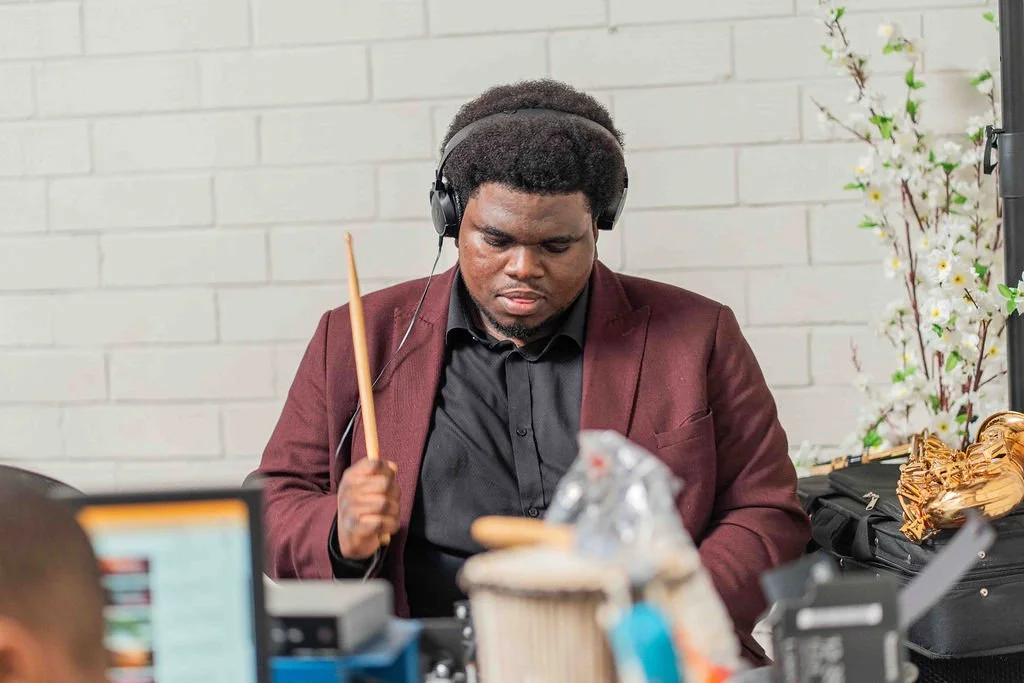 Drummer wearing headphones and holding a drumstick during a recording session