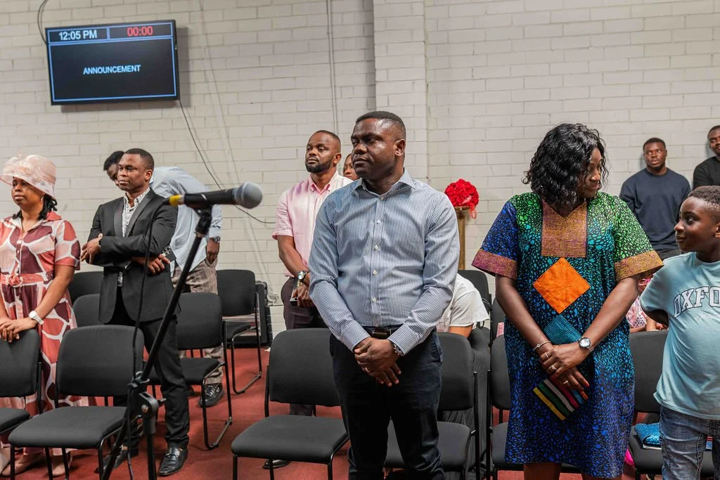 People standing in a meeting room beside a microphone and announcement display.