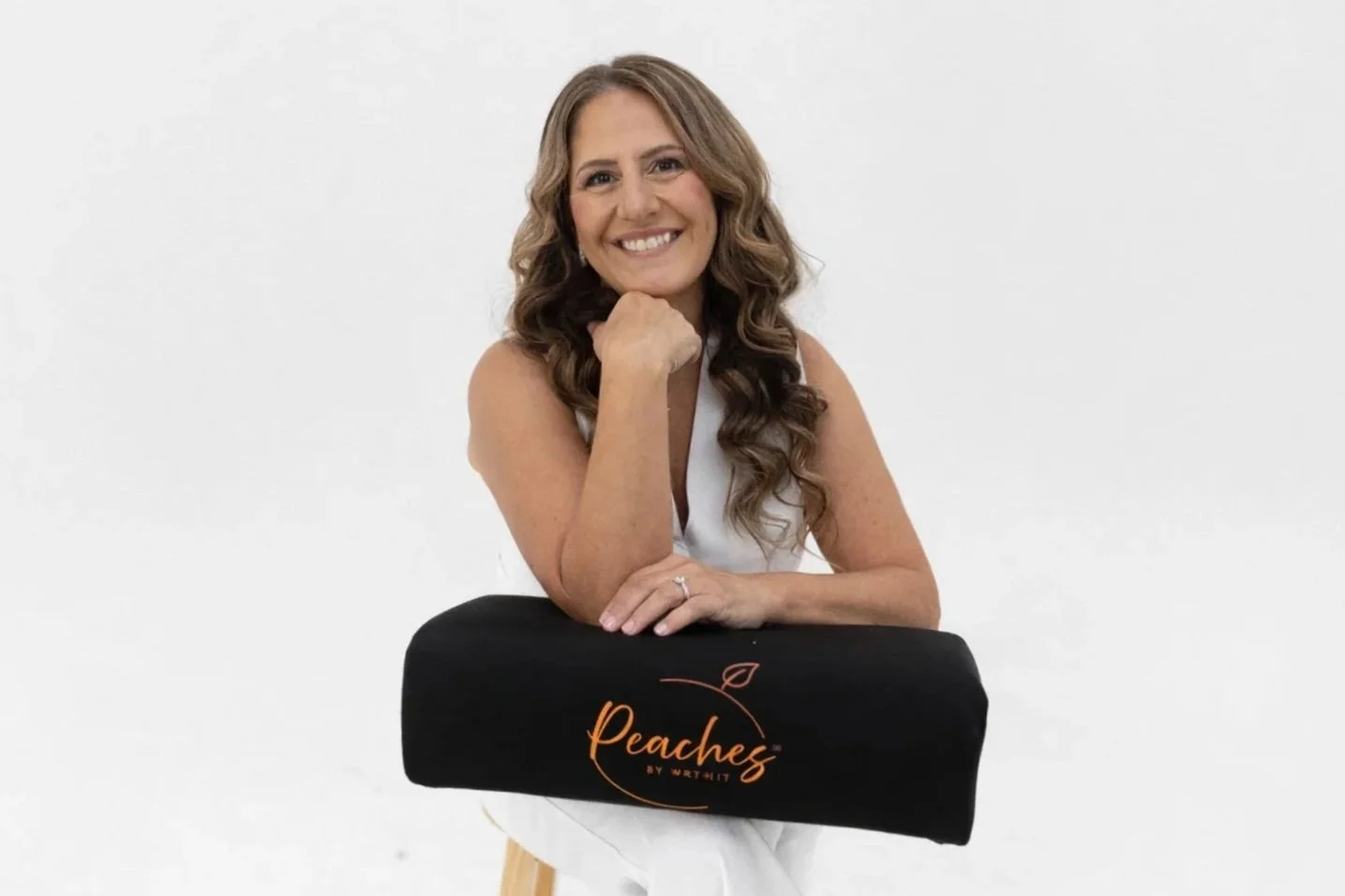 Monica Skalsky, CAMTC #33056, C-MLD, wearing a white vest and white pants sitting with The Bellini BBL Pillow created by Peaches by Wrthit in Murrieta, CA