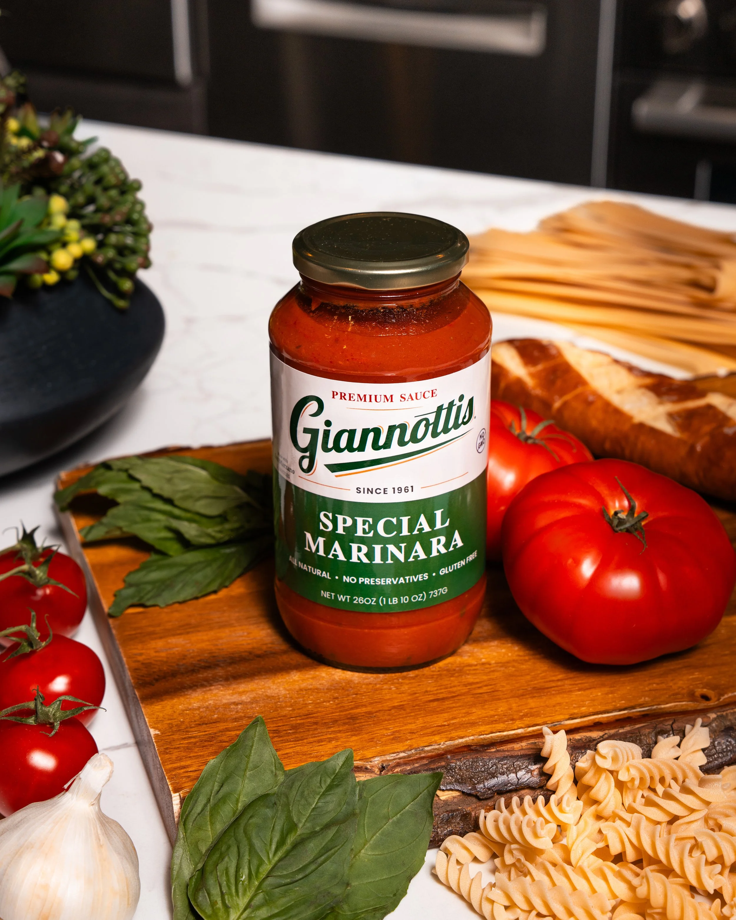 Giannotti’s Special Marinara sauce jar with tomatoes, basil and pasta on a kitchen board