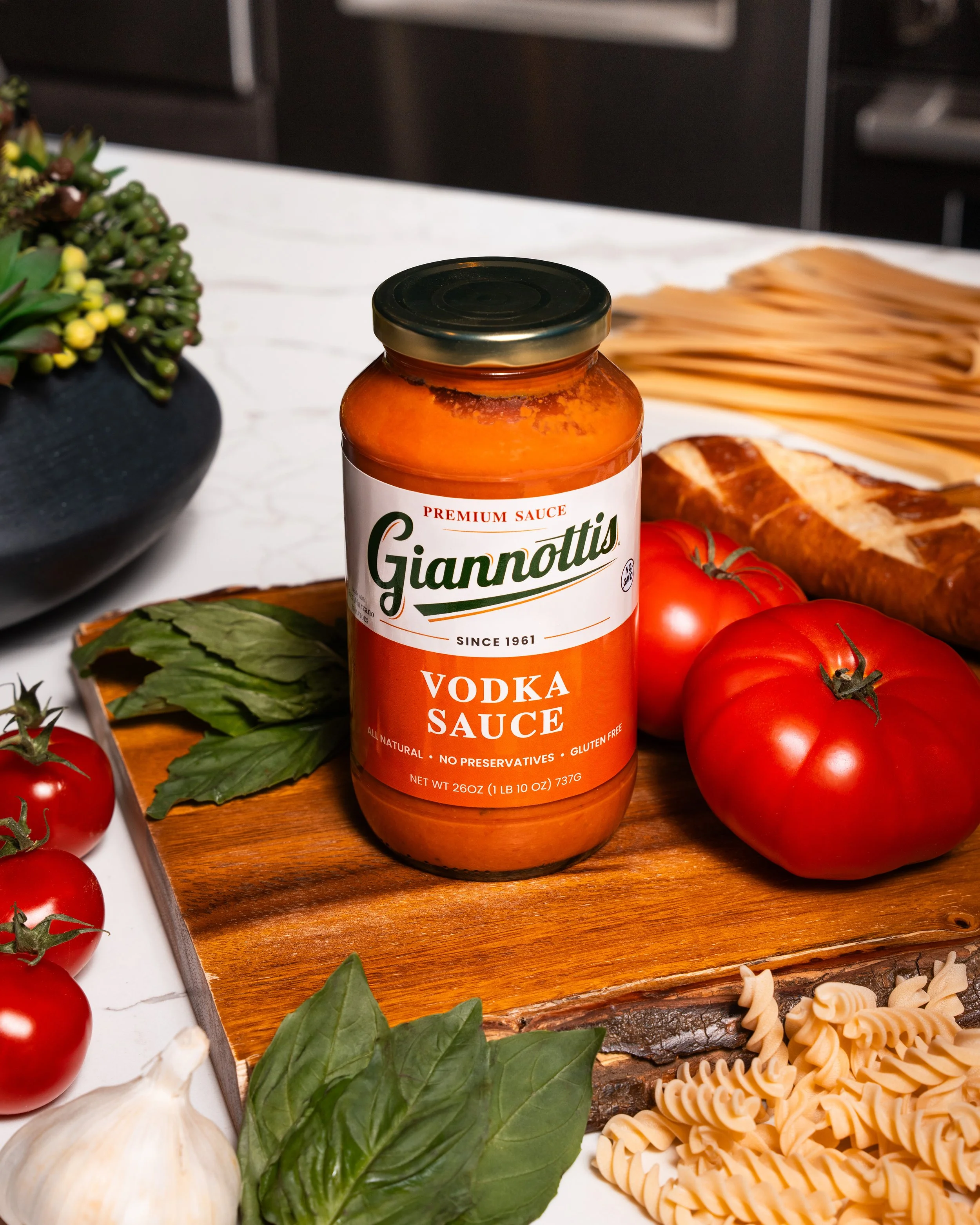 Giannotti’s Vodka Sauce jar with tomatoes, basil and pasta on a kitchen board