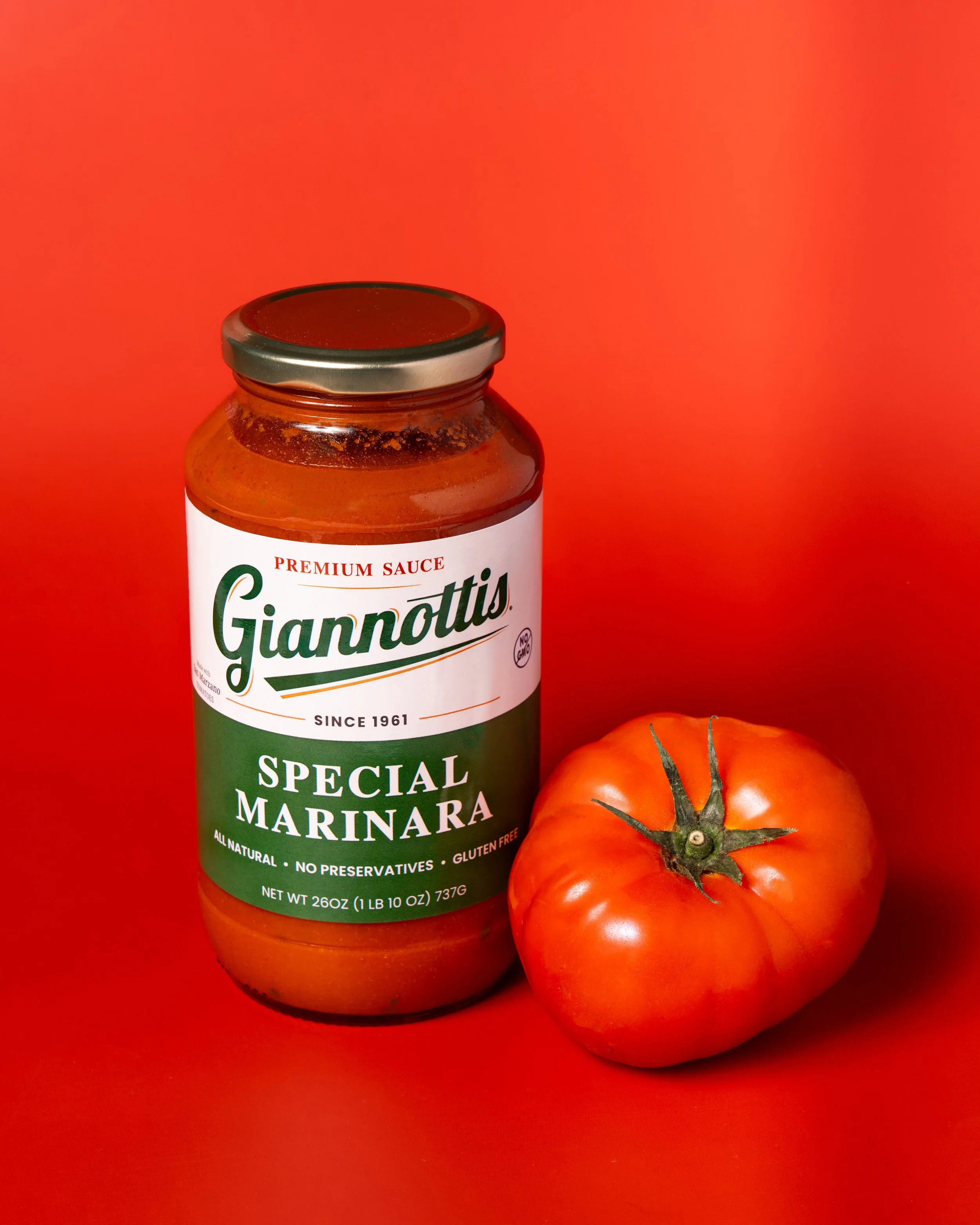 Giannotti’s Special Marinara sauce jar beside a tomato against a red background