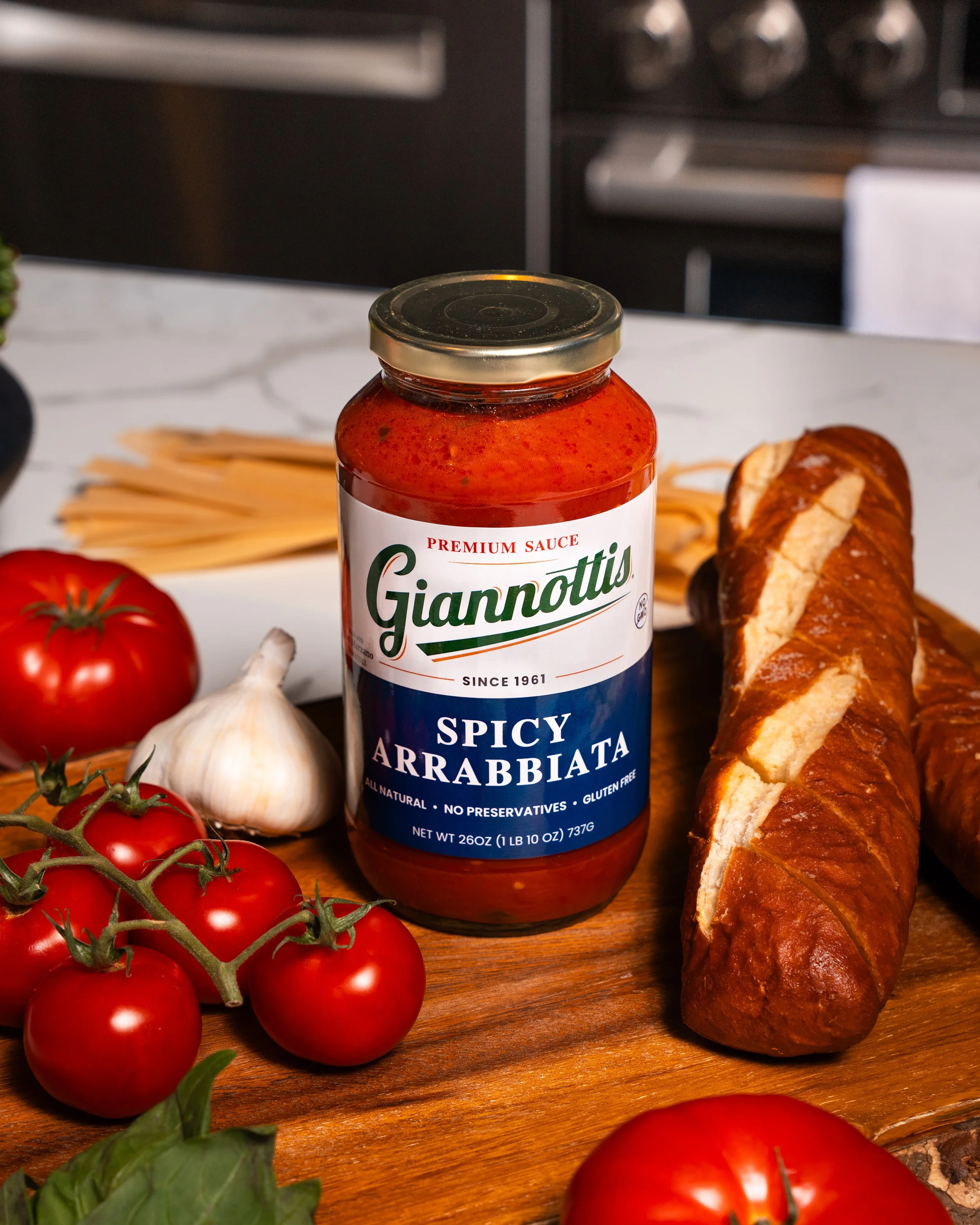 Giannotti’s Spicy Arrabbiata sauce jar with tomatoes, garlic and bread on a kitchen board