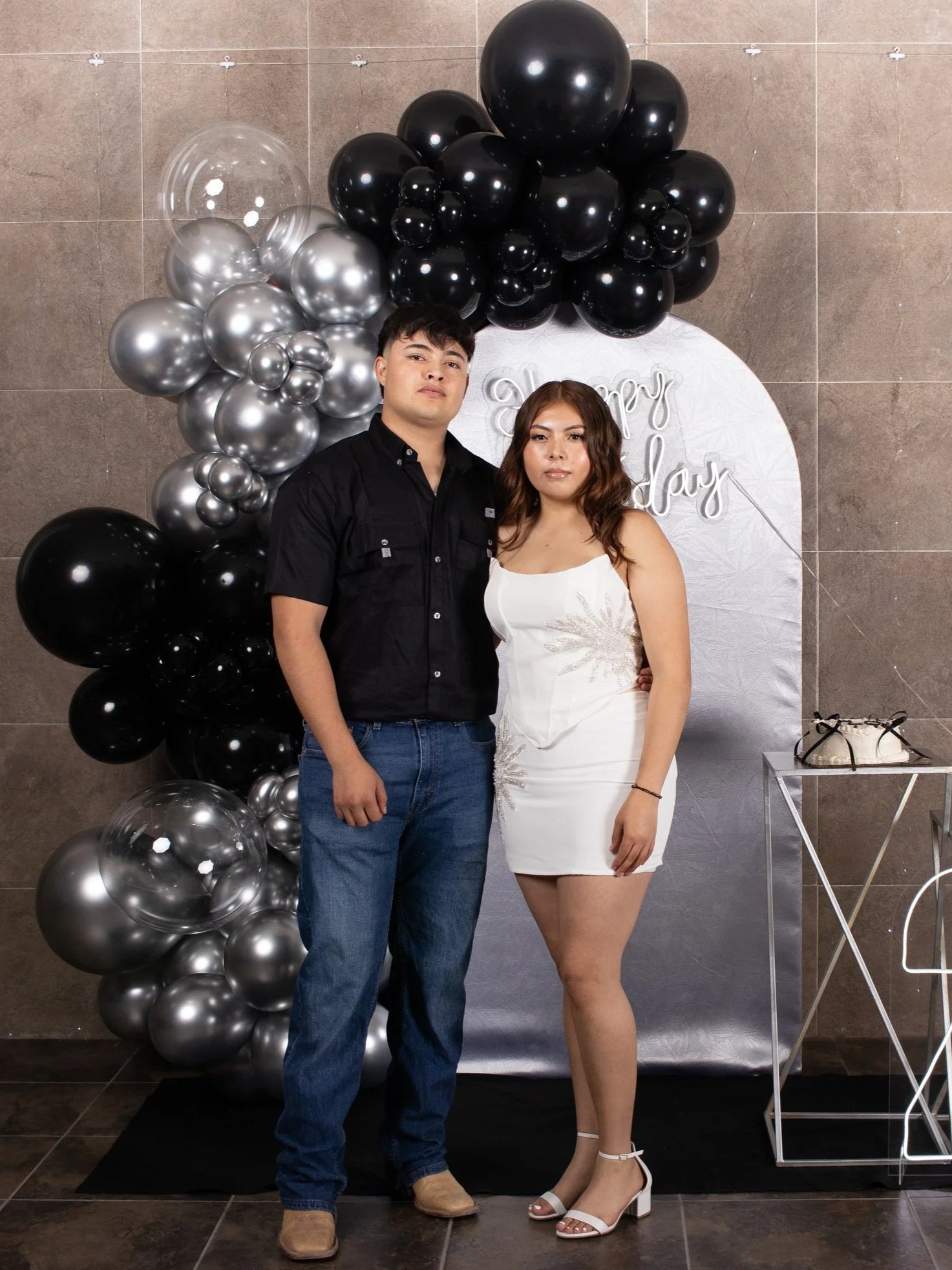 Toma equilibrada con esquema de iluminación uniforme, destacando vestuario claro sobre fondo neutro. La intención es reflejar unión y elegancia dentro del contexto del evento.