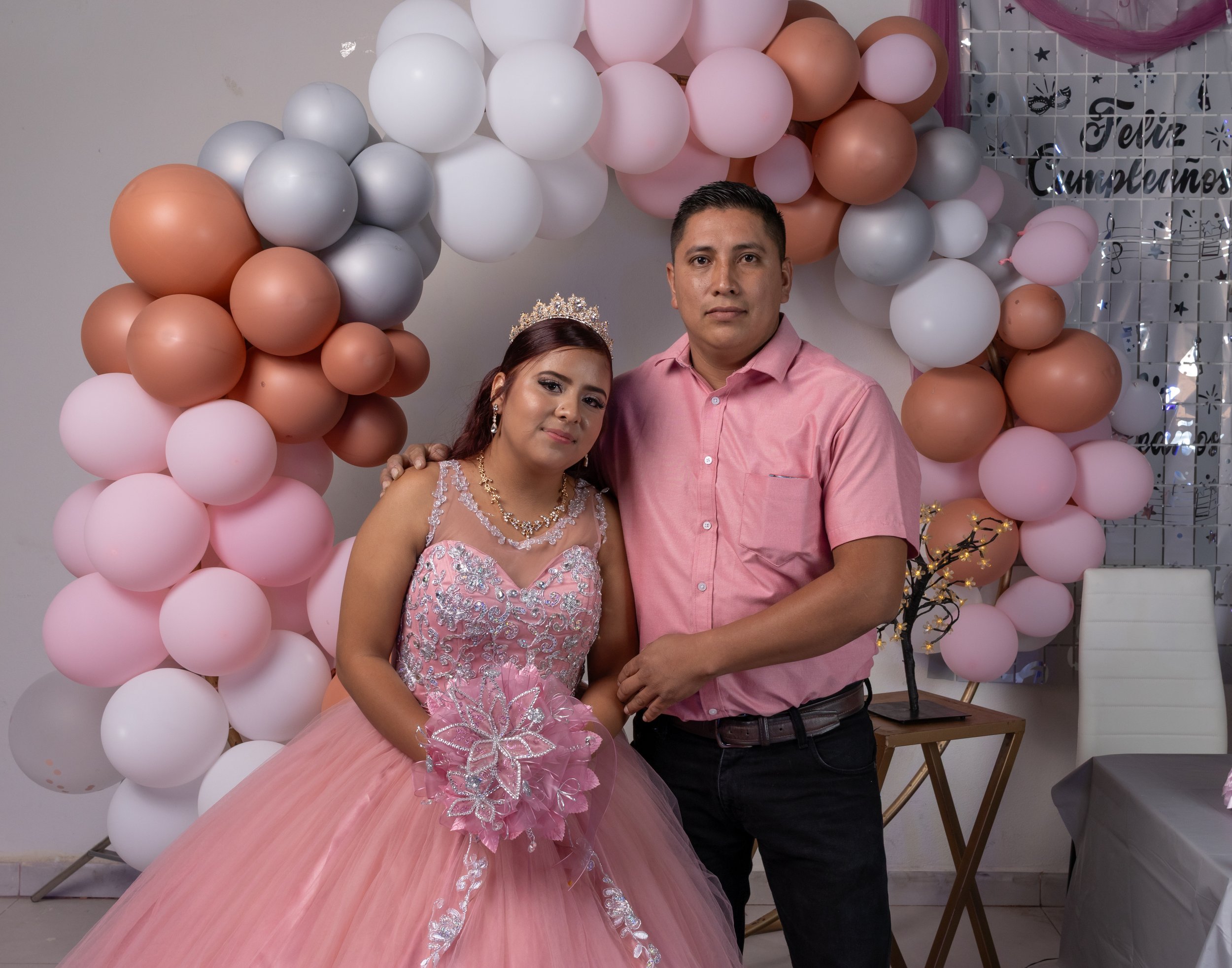 Cuidamos una pose natural y un balance tonal entre vestuario y fondo, logrando una fotografía clásica y significativa que representa apoyo y amor familiar.