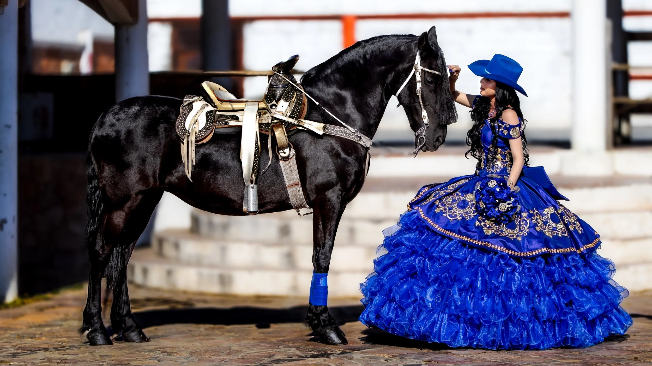 Plano lateral para equilibrar la elegancia del caballo y el volumen del vestido. Profundidad de campo corta que separa sujetos del fondo y mantiene detalle en la silla charra.