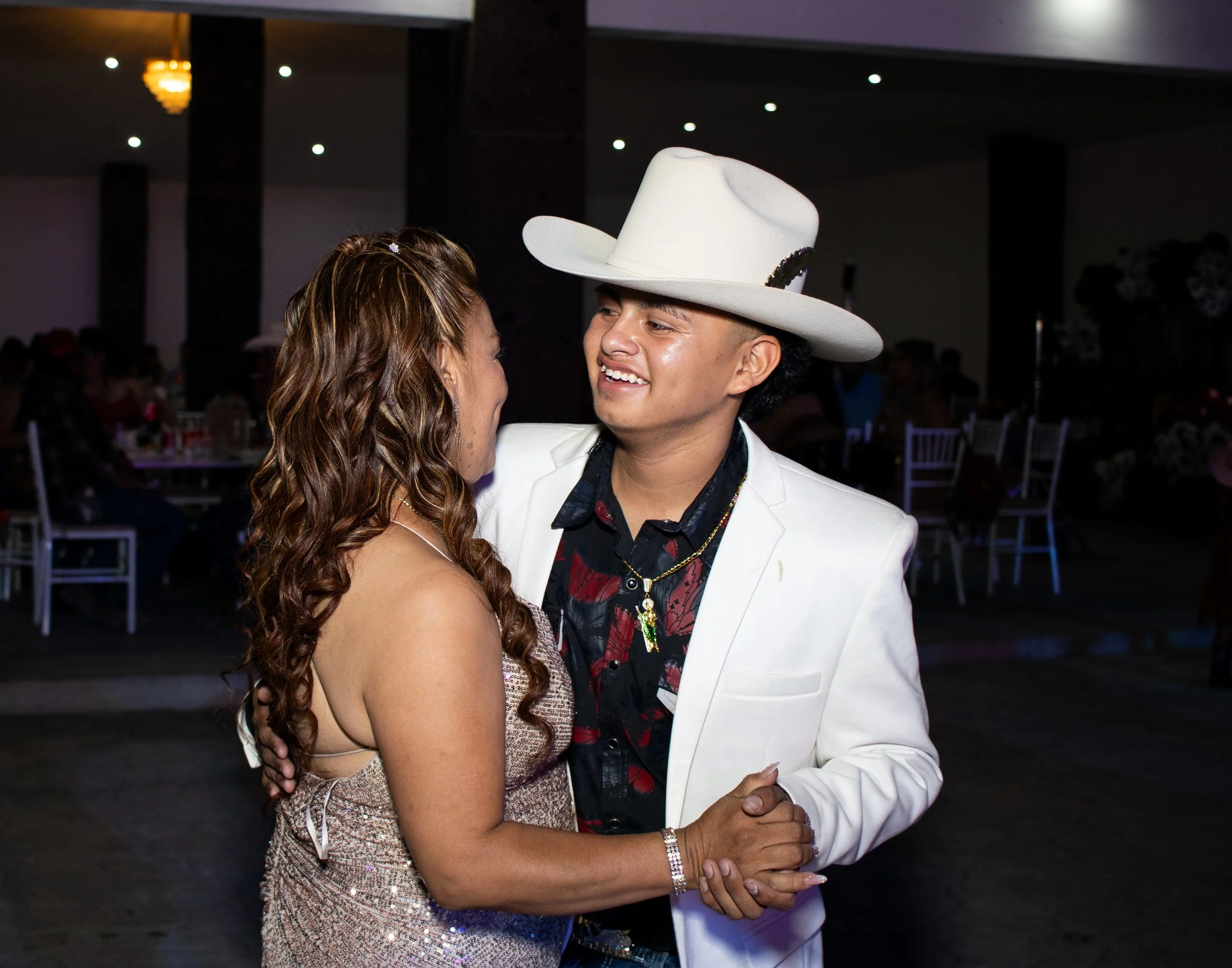 Plano medio íntimo con recorte de luz que separa a la pareja del ambiente. Buscamos gestos y miradas para contar la emoción del momento sin distracciones.
