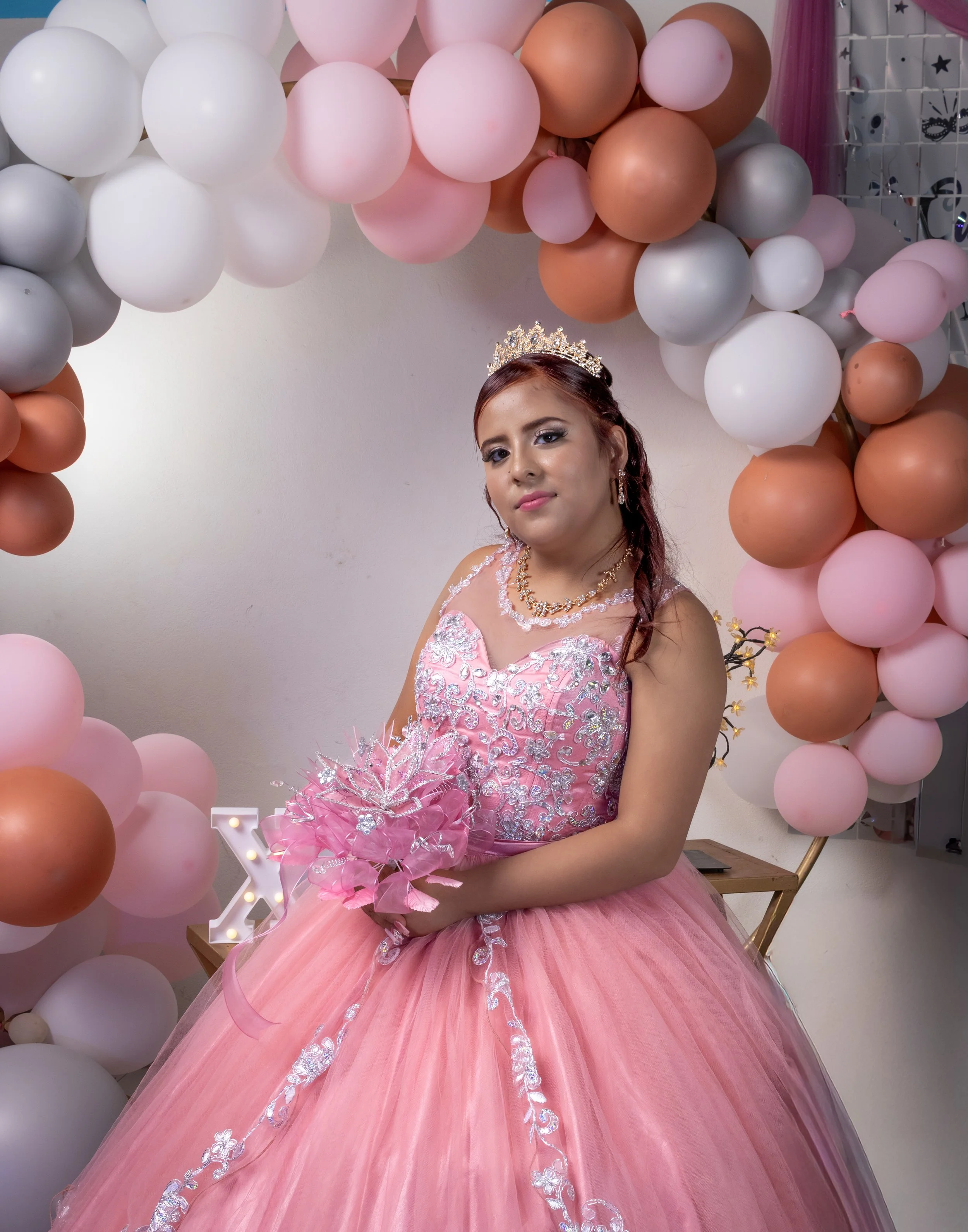Capturamos a la quinceañera en su mejor luz, destacando el diseño del vestido, los tonos suaves del decorado y la armonía entre la composición y la iluminación, creando una imagen de ensueño.