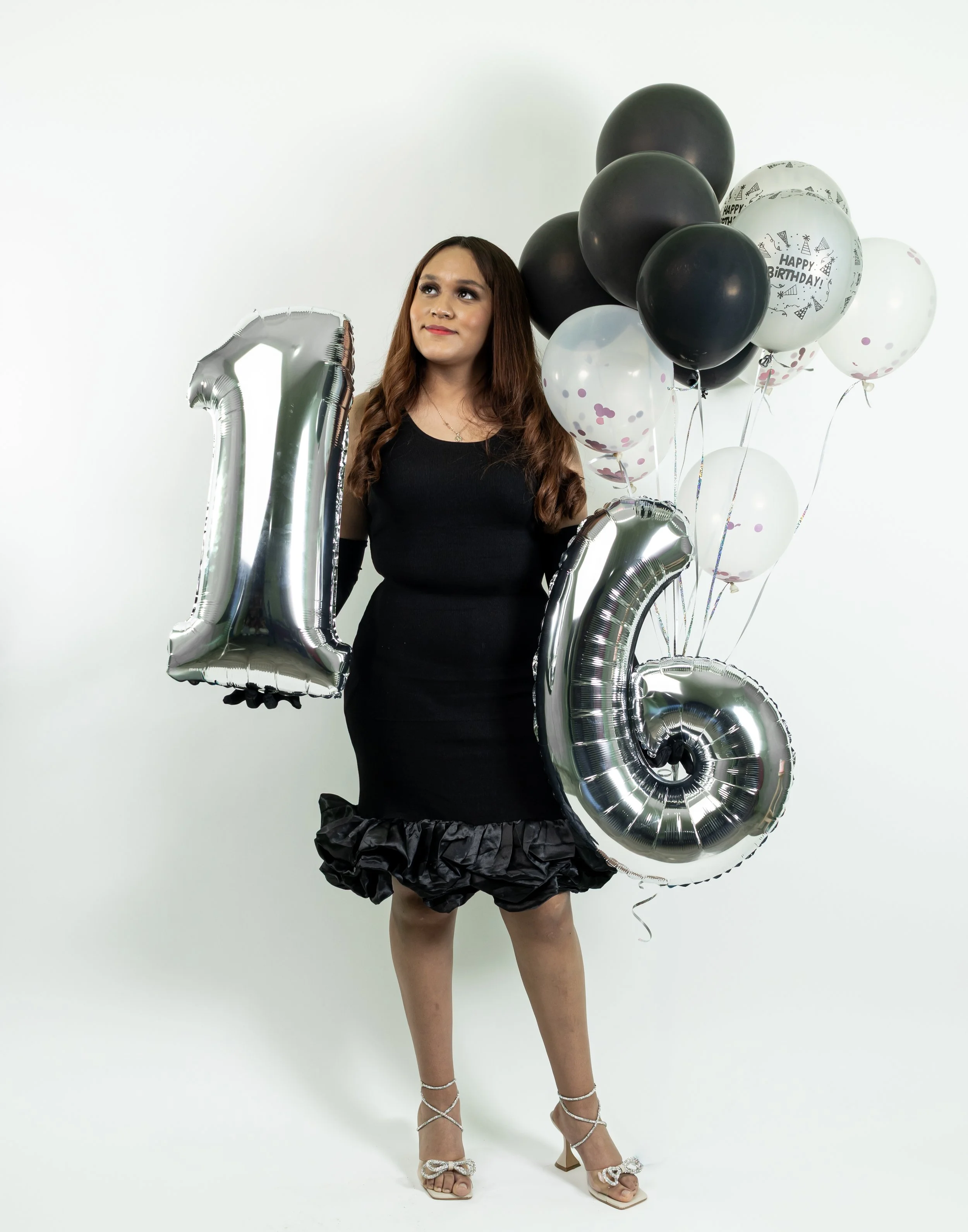 Los globos plateados con el número "16" destacan el motivo de la sesión. La iluminación suave y las sombras equilibradas enfatizan la expresión facial, resaltando madurez y estilo.