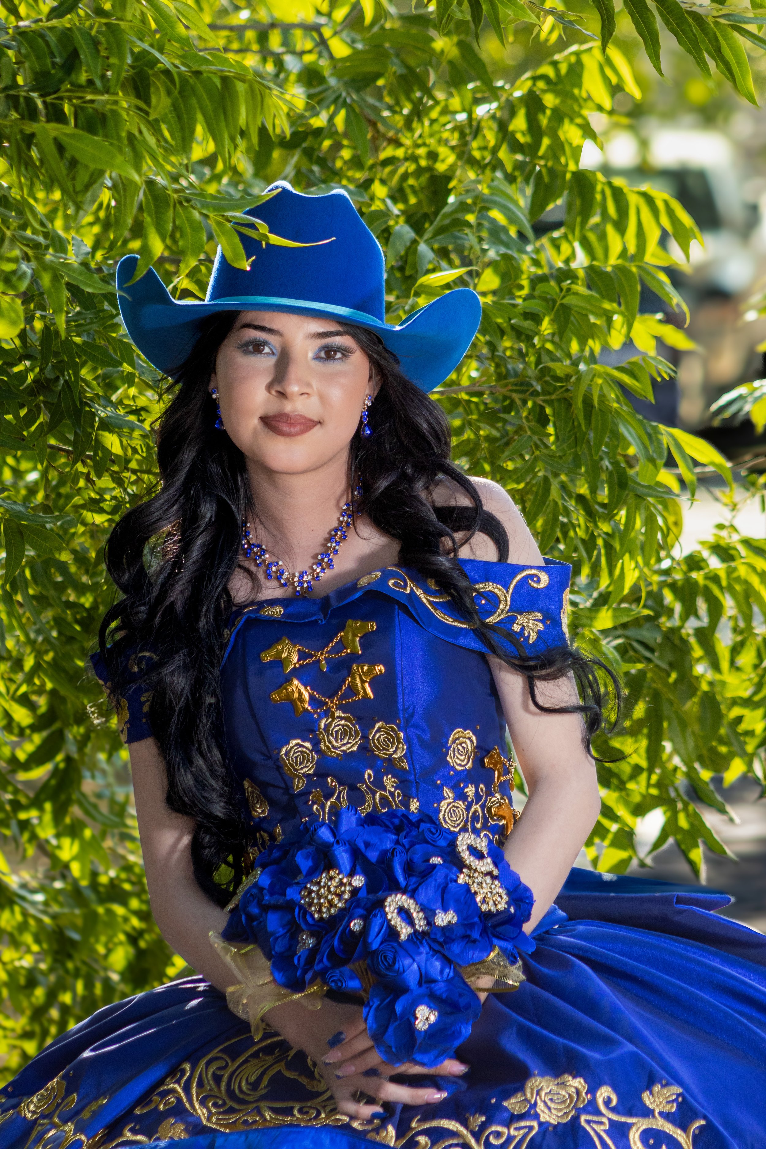 Composición íntima con hojas como bokeh natural. Relleno de flash sutil para ojos brillantes y contraste perfecto entre el verde y el azul del atuendo.