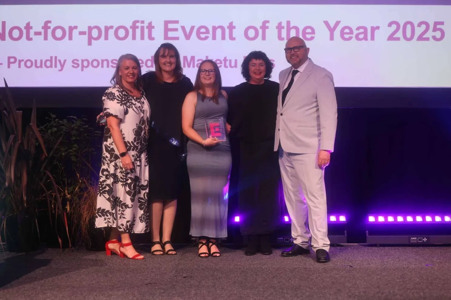 Group of five people standing on stage during an award ceremony at the NZEA Event awards receiving a award for Community or Not-for-profit (under 3000 participants) Event of the Year 2025