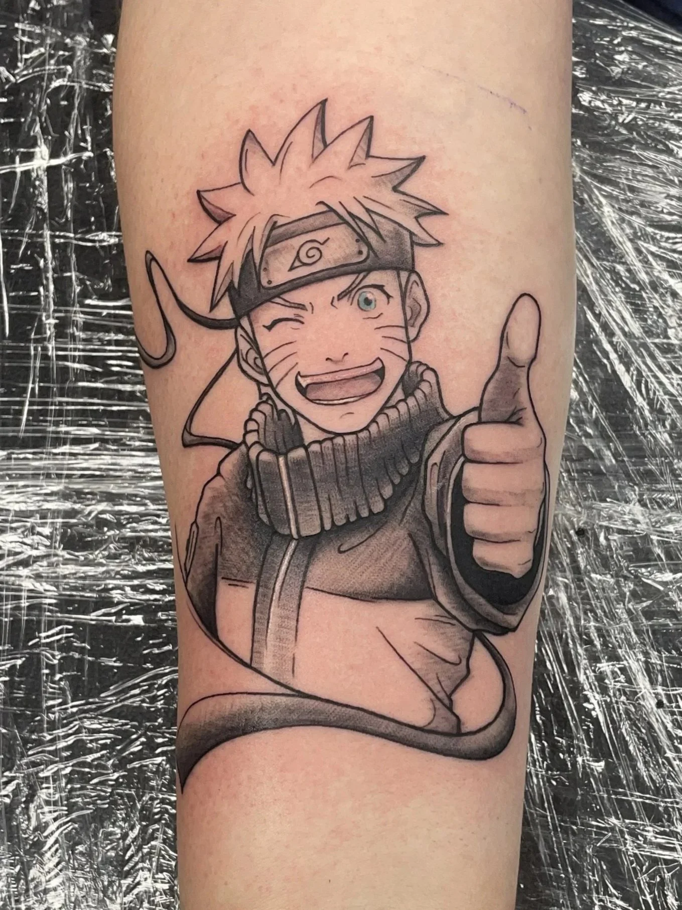 custom Naruto tattoo, client requested the winking eye, open mouth smile, and thumbs up, tattooed by Zing Phelps, in Cedar Rapids, Iowa
