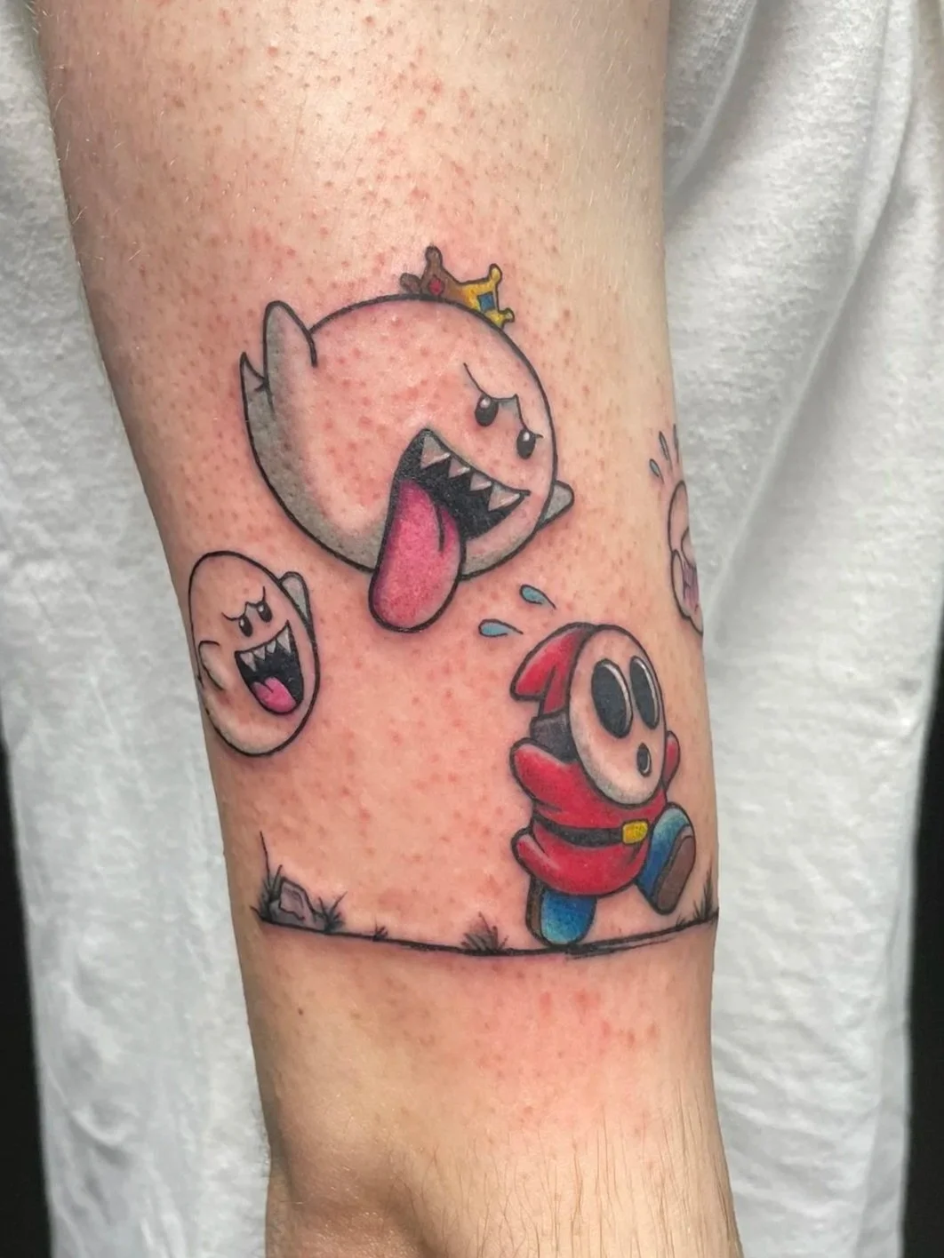 Colorful tattoo of characters from Super Mario on person's arm, including a shy guy, king boo, tattooed by Zing Phelps, in Cedar Rapids, Iowa