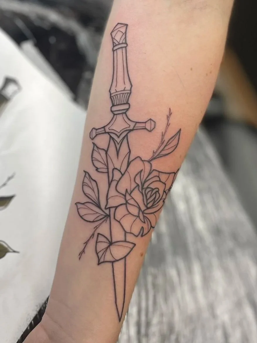 Tattoo of a sword with floral elements on a person's forearm, tattooed by Zing Phelps, in Cedar Rapids, Iowa