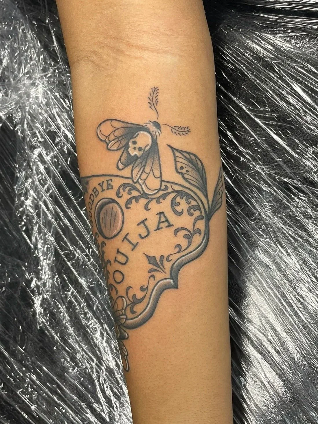 Ouija Board piece surrounded in death moths, tattooed by Zing Phelps, in Cedar Rapids, Iowa