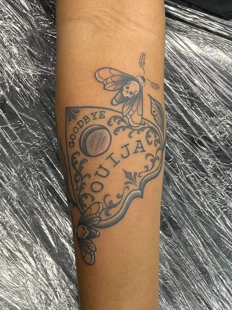 Ouija board piece with death moths on a forearm,  tattooed by Zing Phelps, in Cedar Rapids, Iowa