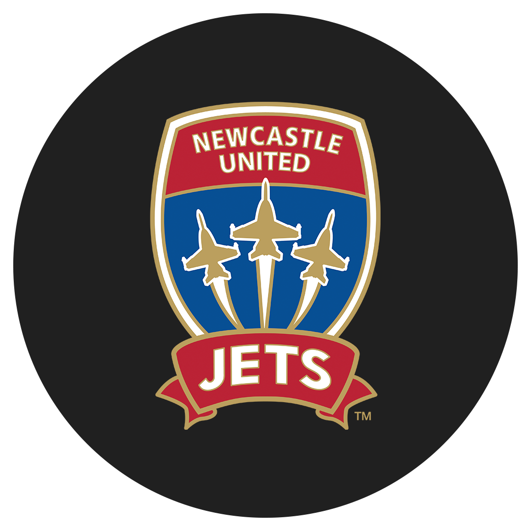 Close-up of a Newcastle United Jets team logo featuring three jets flying upward within a shield, with red, blue, and gold colors, on a black background.