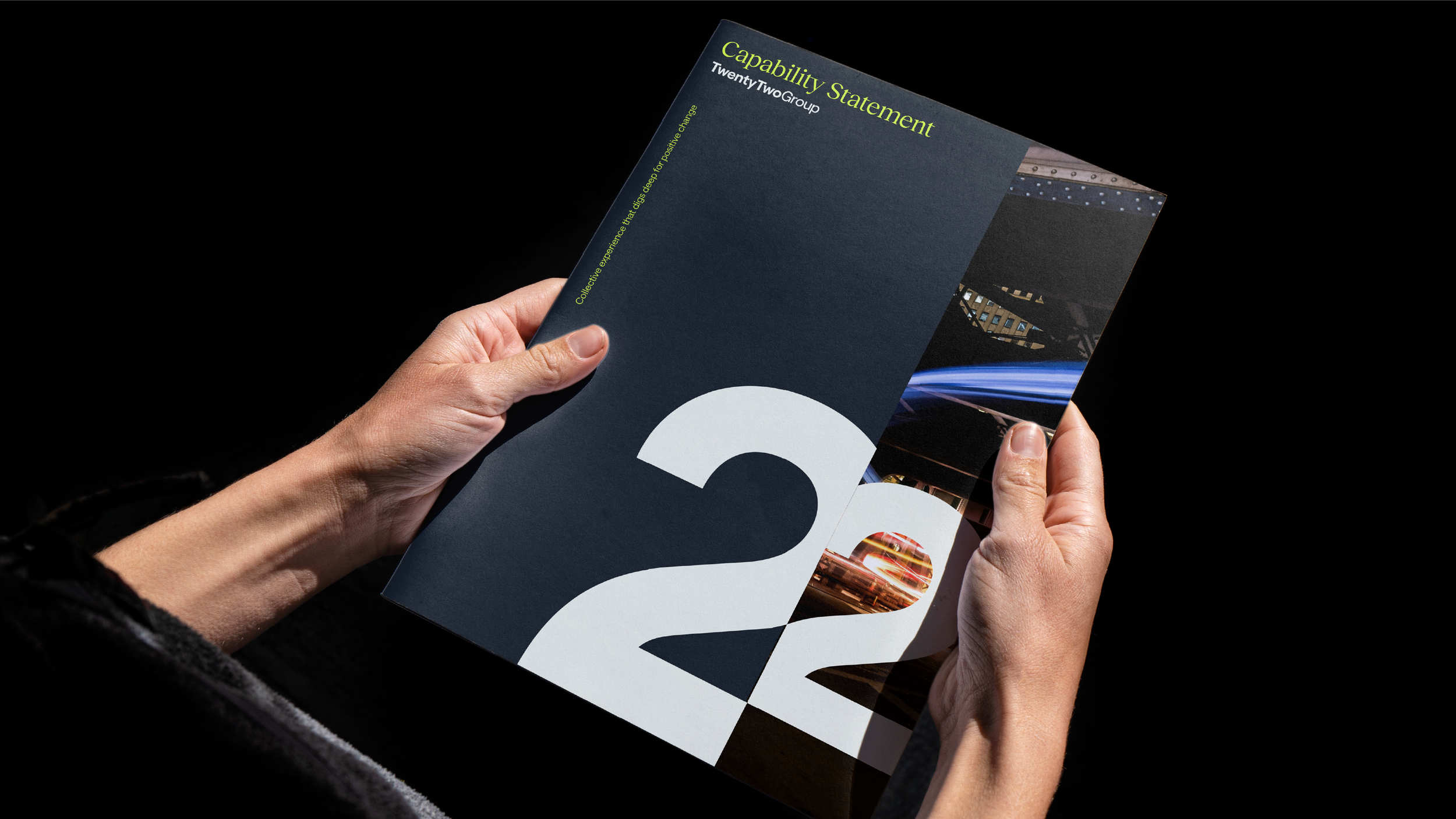 Person holding a brochure titled "Capability Statement" with a large number "22" on the cover and abstract cityscape images inside.
