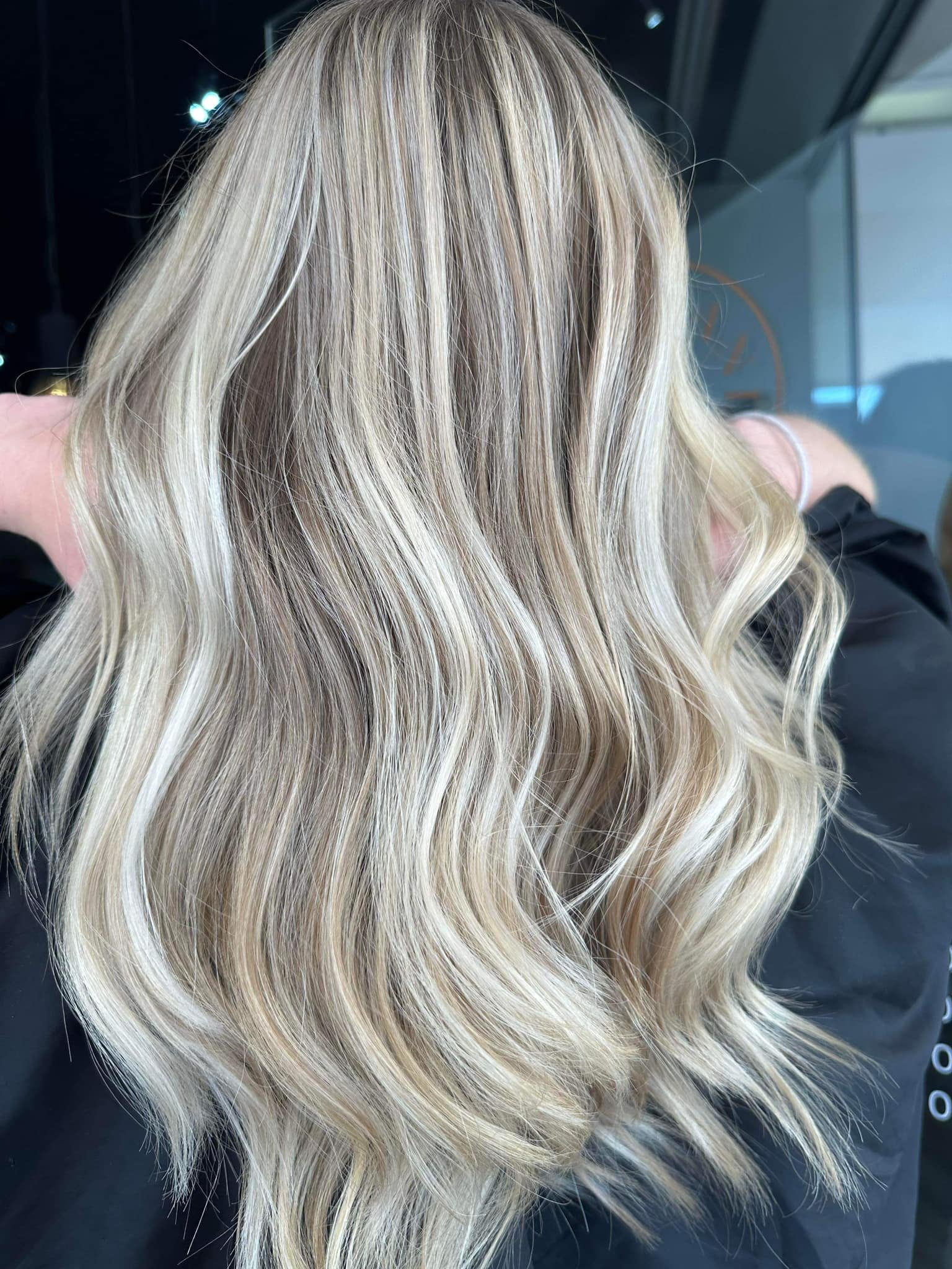 Blonde wavy hair from behind in a salon or studio setting.