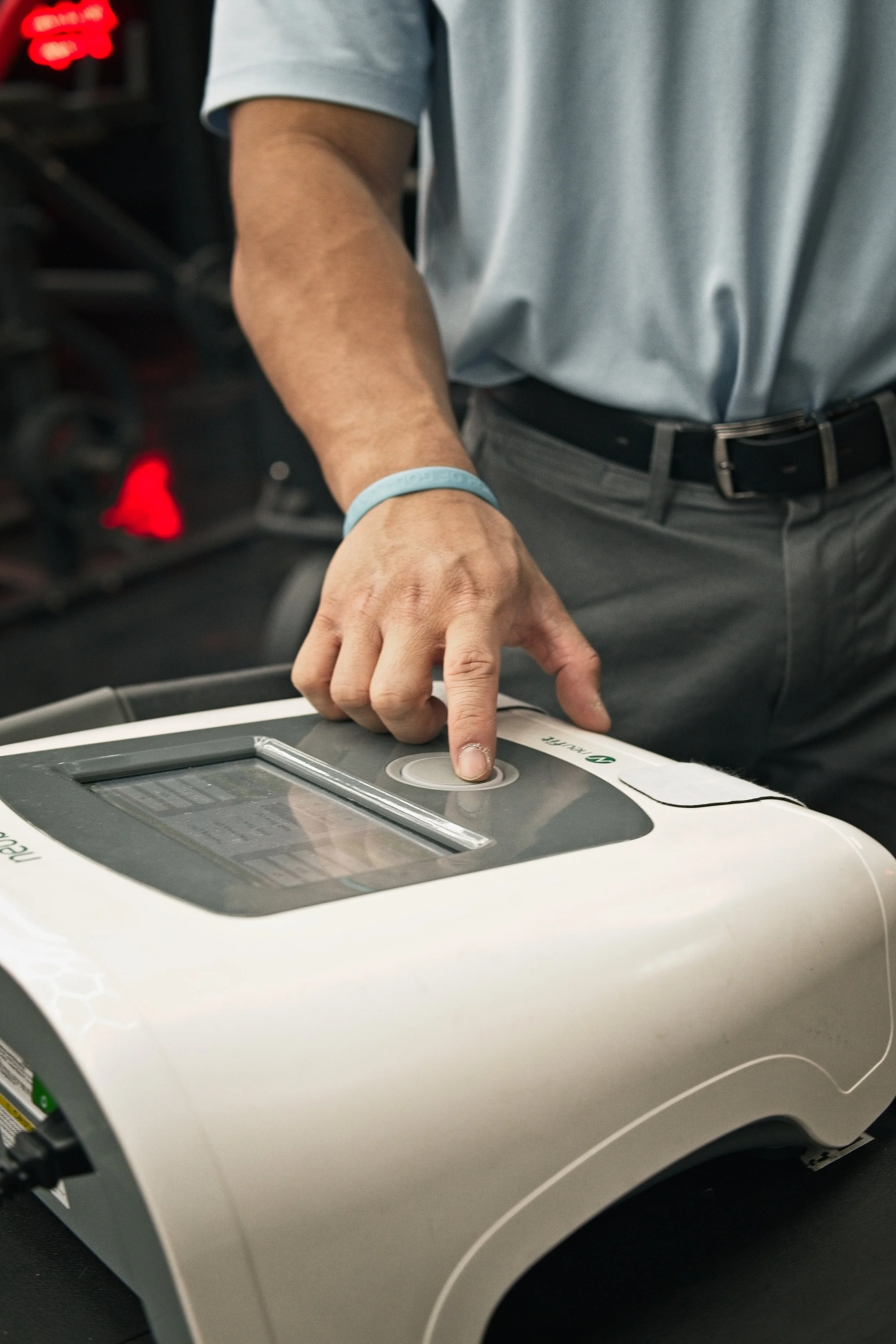 A person in a gray shirt pressing a button on a medical device or equipment.