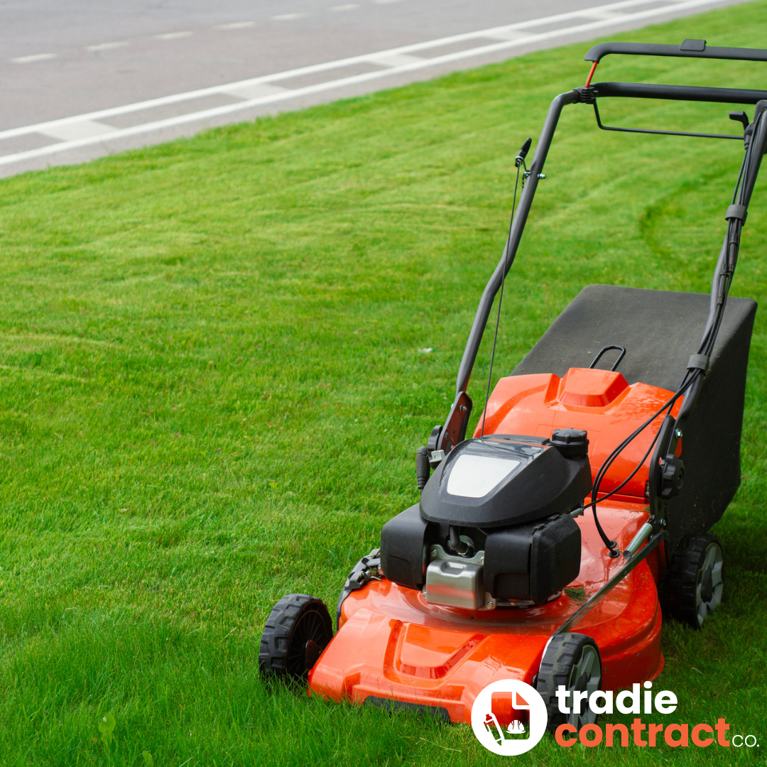 An orange and black gas-powered lawn mower on a well-maintained green lawn near a paved street.