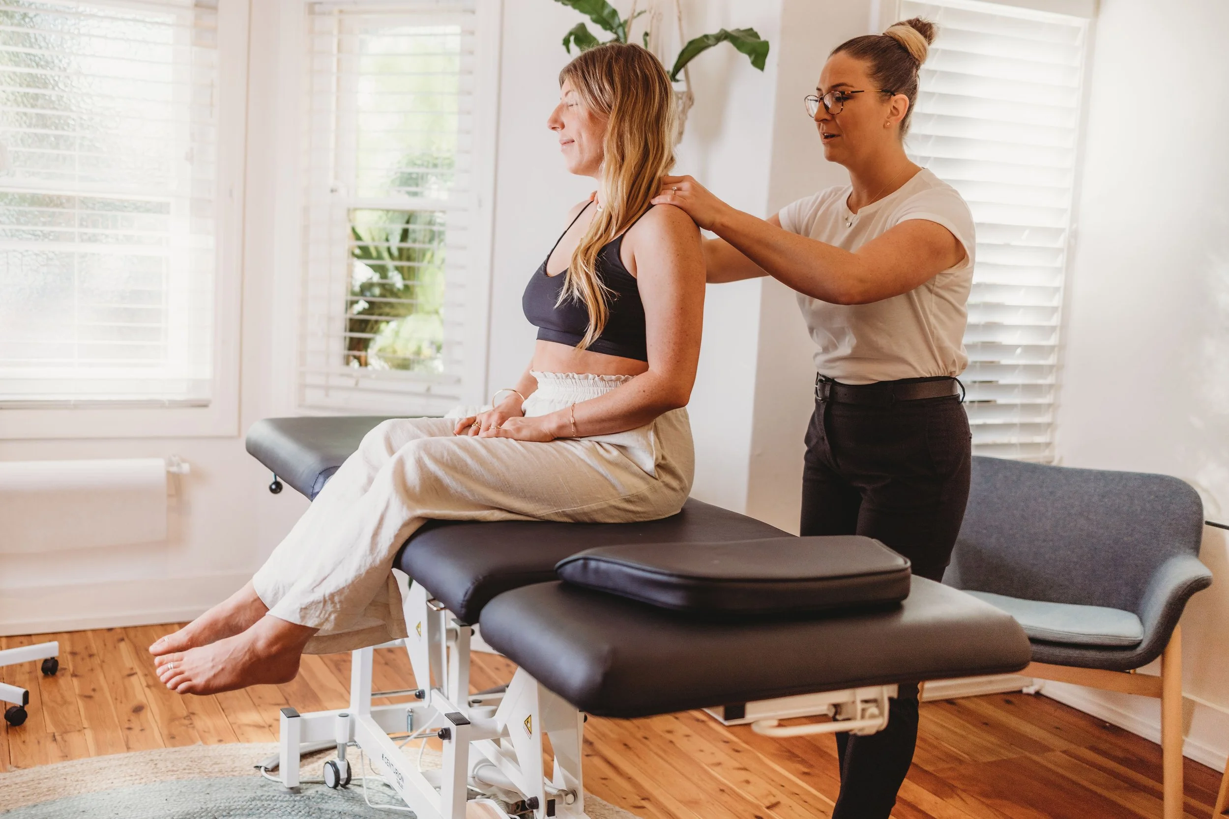 Dr Katie MacRae assessing a patient’s neck during a chiropractic consultation at Valla Health Collective in Curl Curl.