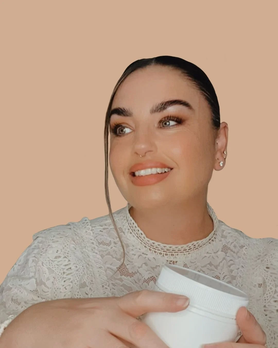 A photo of Melissa White wearing a beige lace top holding a white supplement container smiling.