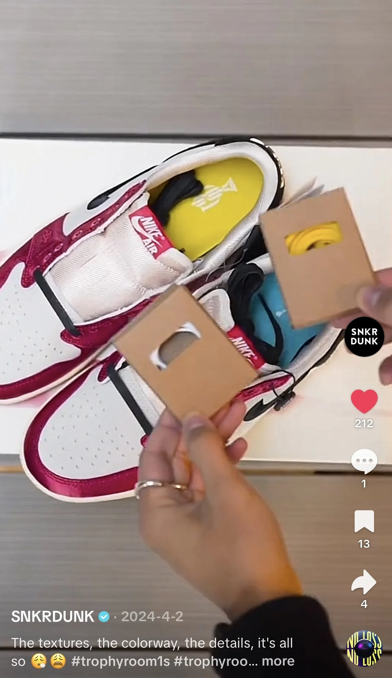 A pair of white Nike sneakers with red accents, each with a small cardboard box containing yellow and blue accessories, possibly shoelaces, held above the shoes.