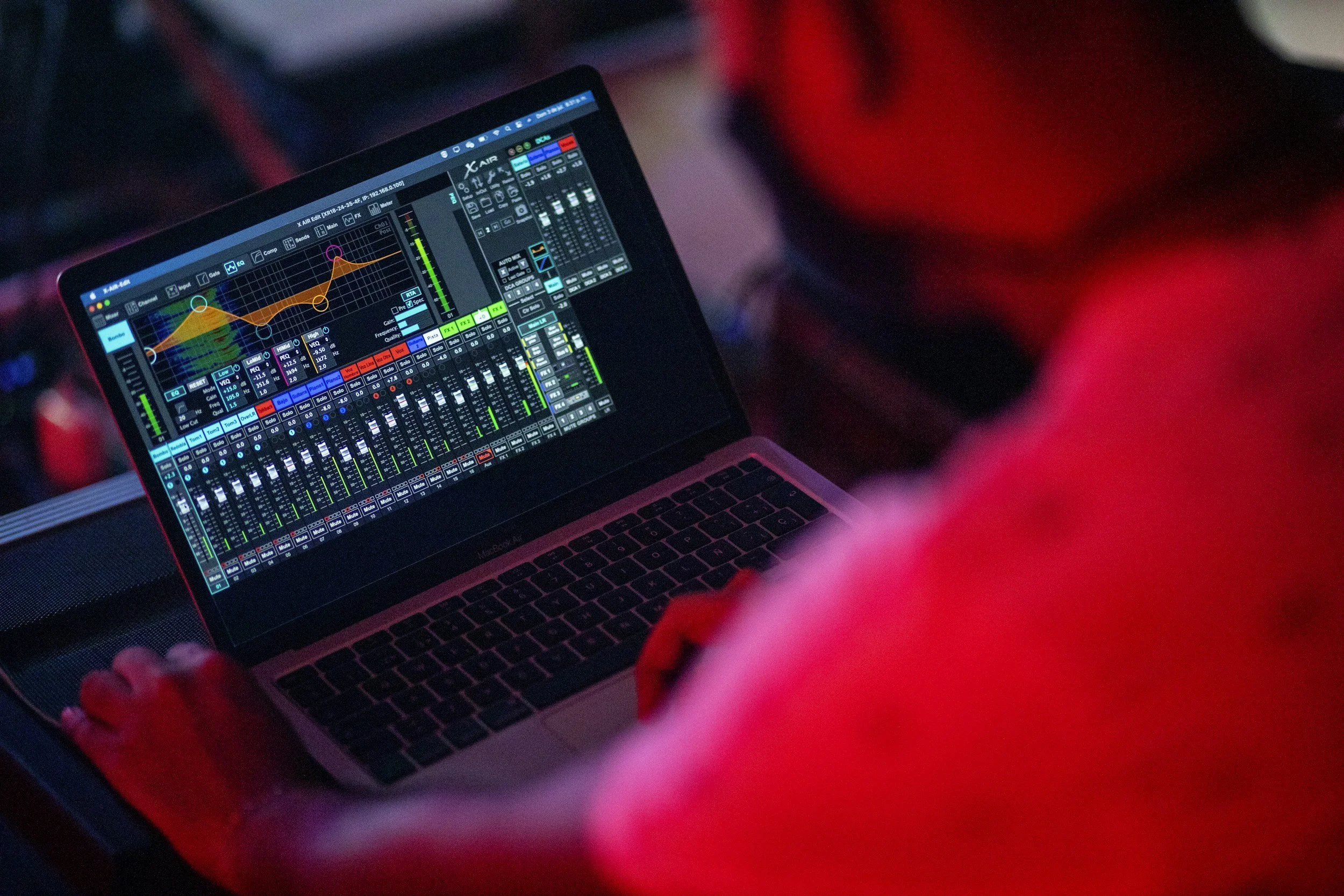 Person using a laptop with a digital audio workstation software open, displaying equalizer, mixer, and audio controls.