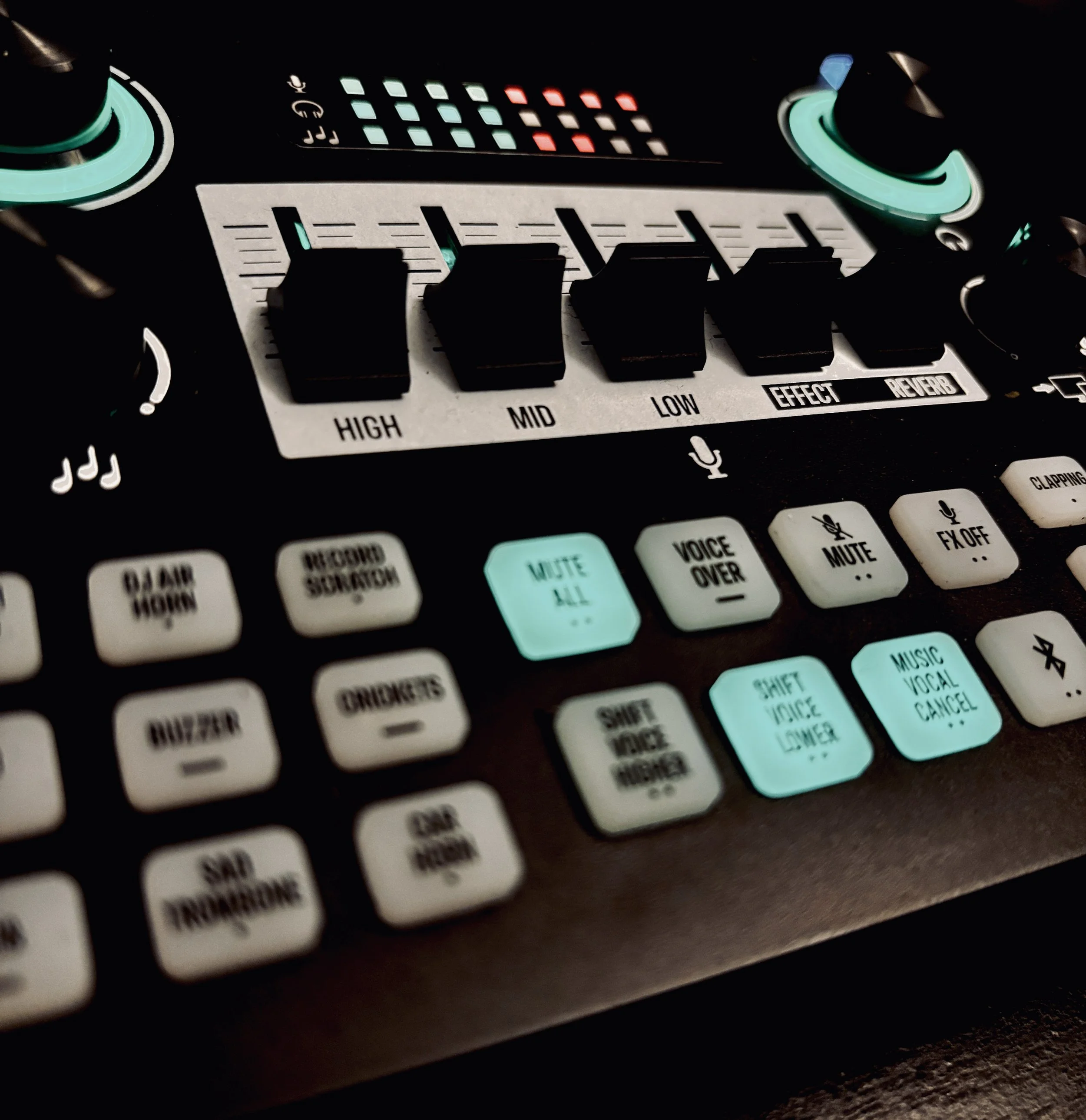 A DJ or music production controller with illuminated buttons, knobs, and sliders, including high, mid, and low frequency controls, effects, and reverb buttons.