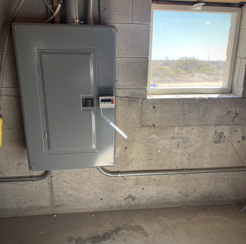 electrician installing whole-home surge protector at breaker panel