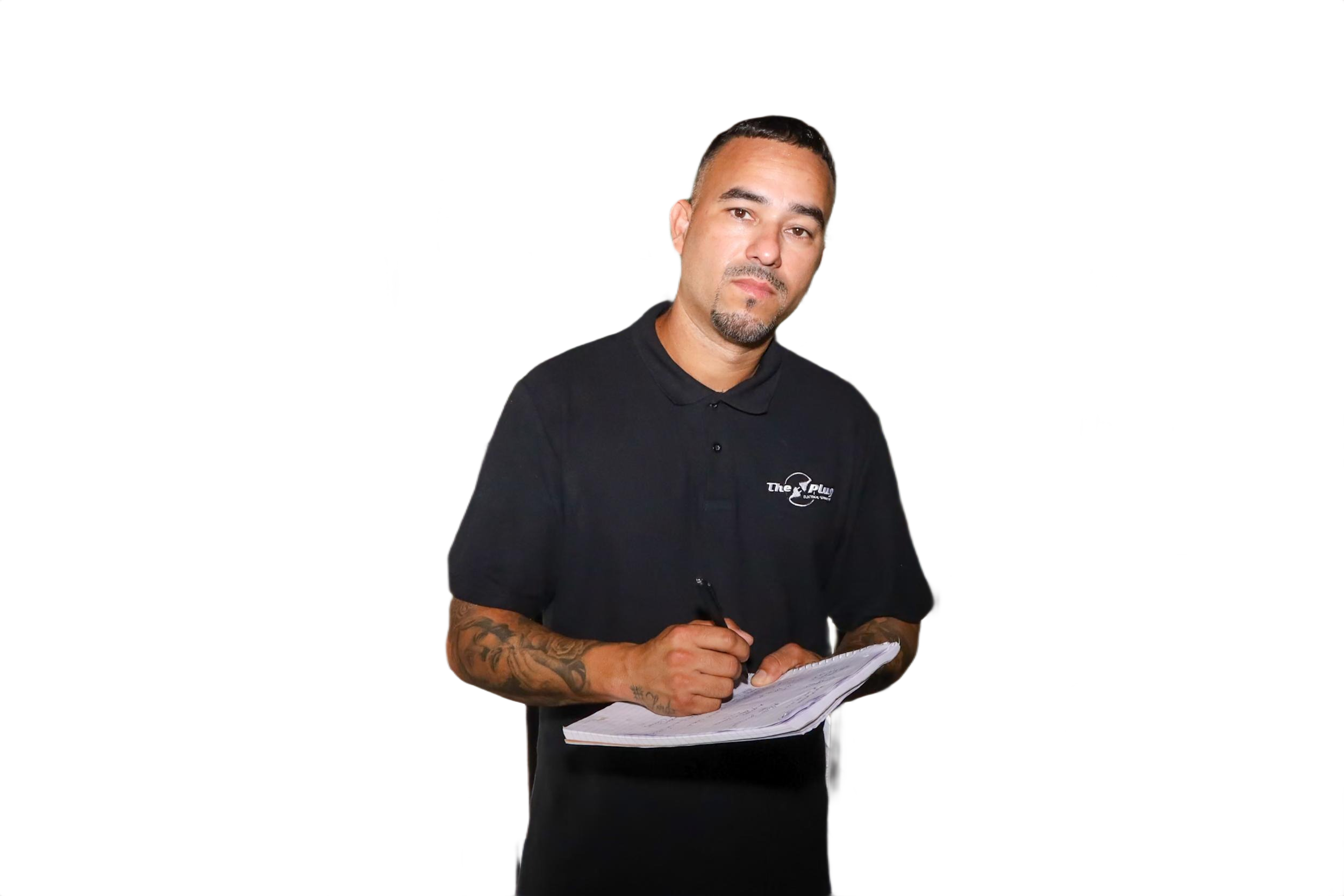 A man in a black polo shirt with tattoos on his right arm is holding a pen and notepad, looking at the camera with a neutral expression.