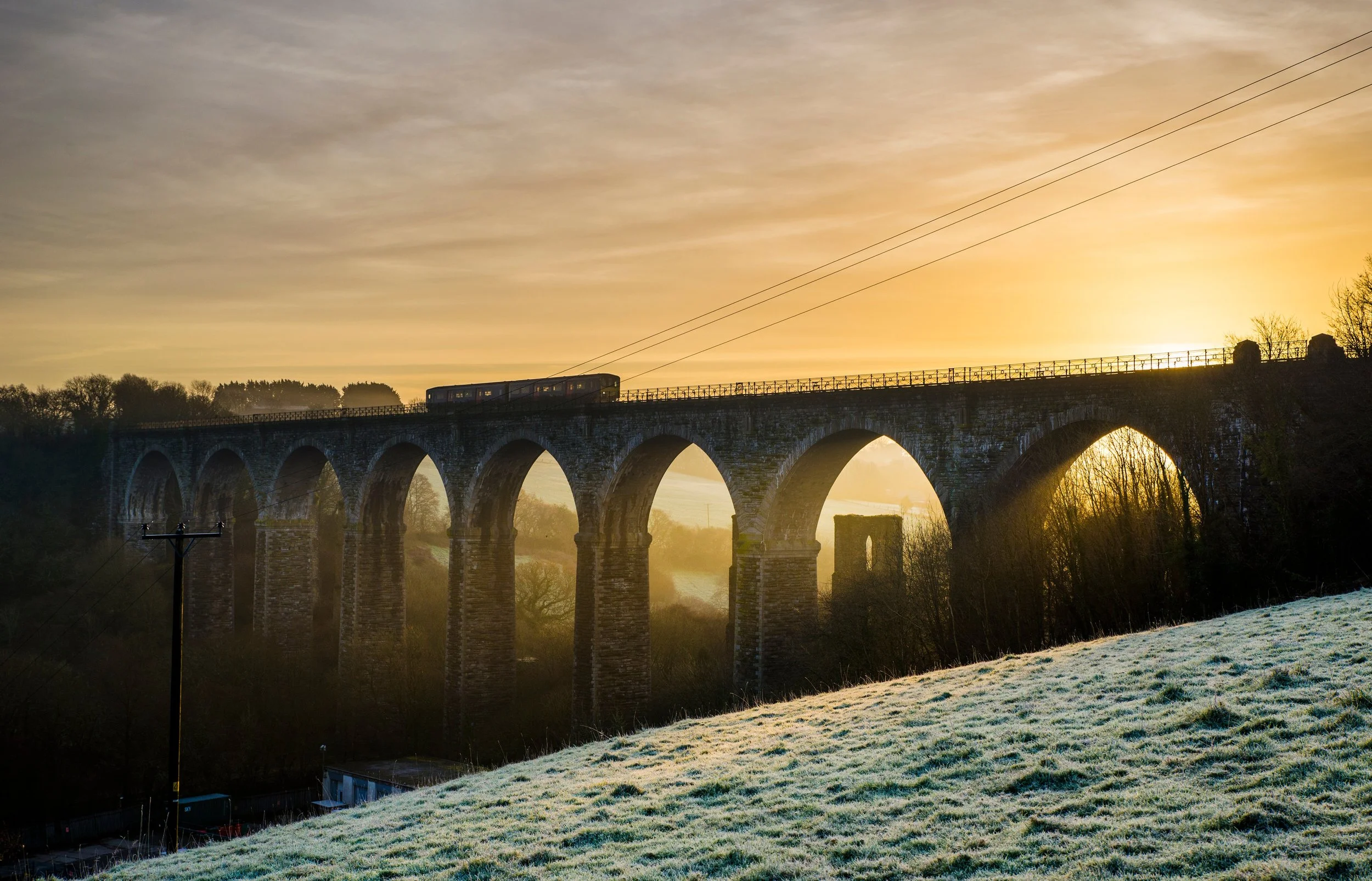 Stone viaduct at sunrise spanning a misty landscape, symbolising structure, connection and forward-looking governance.
