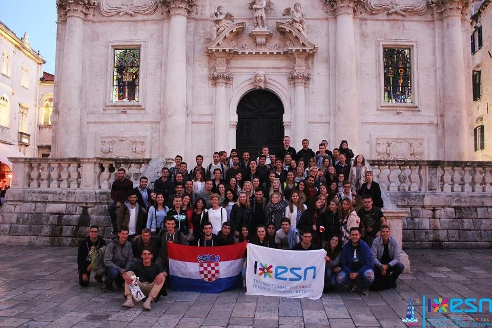 Grupo de pessoas em frente a uma igreja antiga, segurando bandeiras da Croácia e do programa de intercâmbio ESN.
