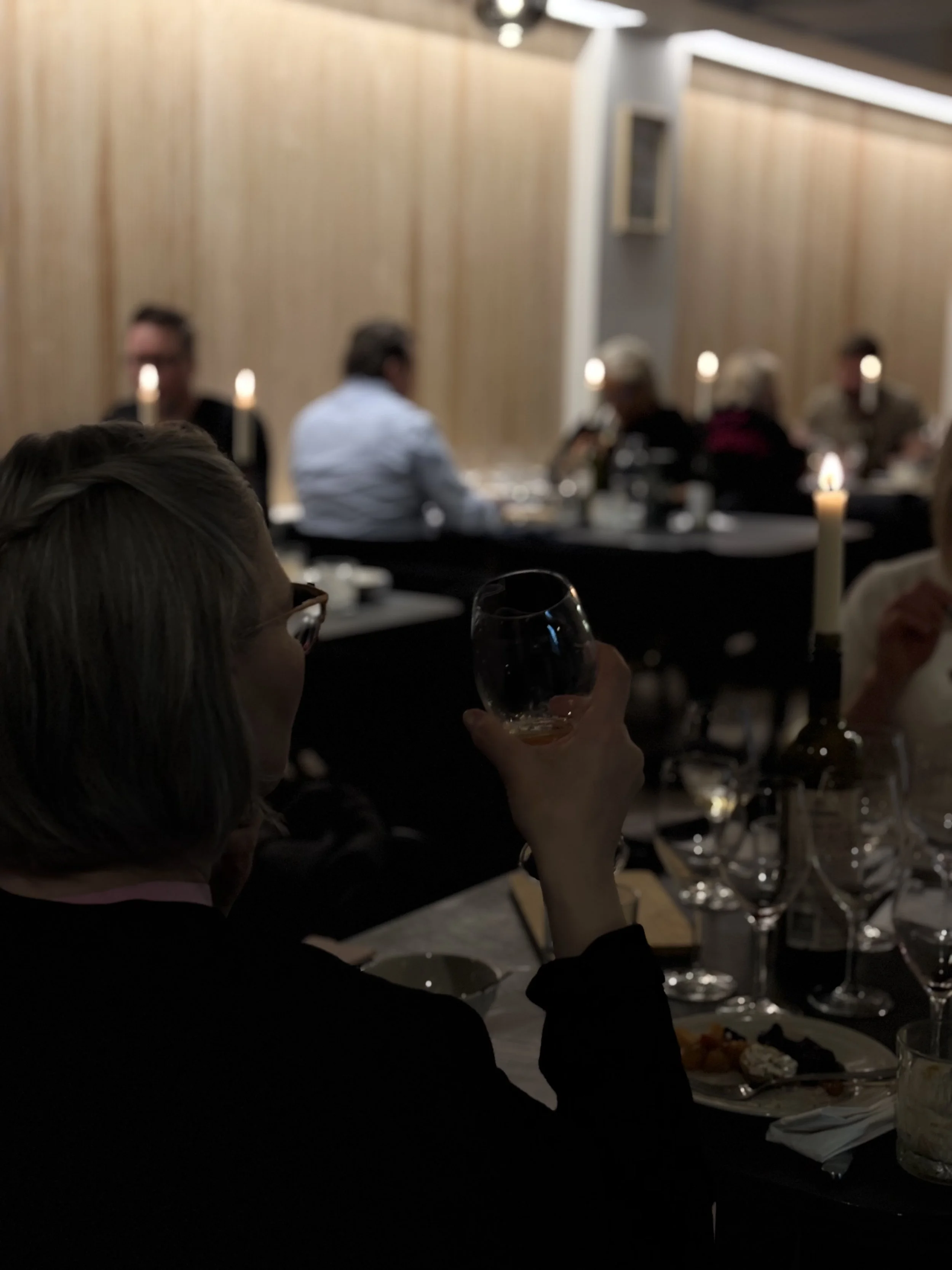 ihmisiä ravintolapöydissä, kaunis kattaus ja kynttilät