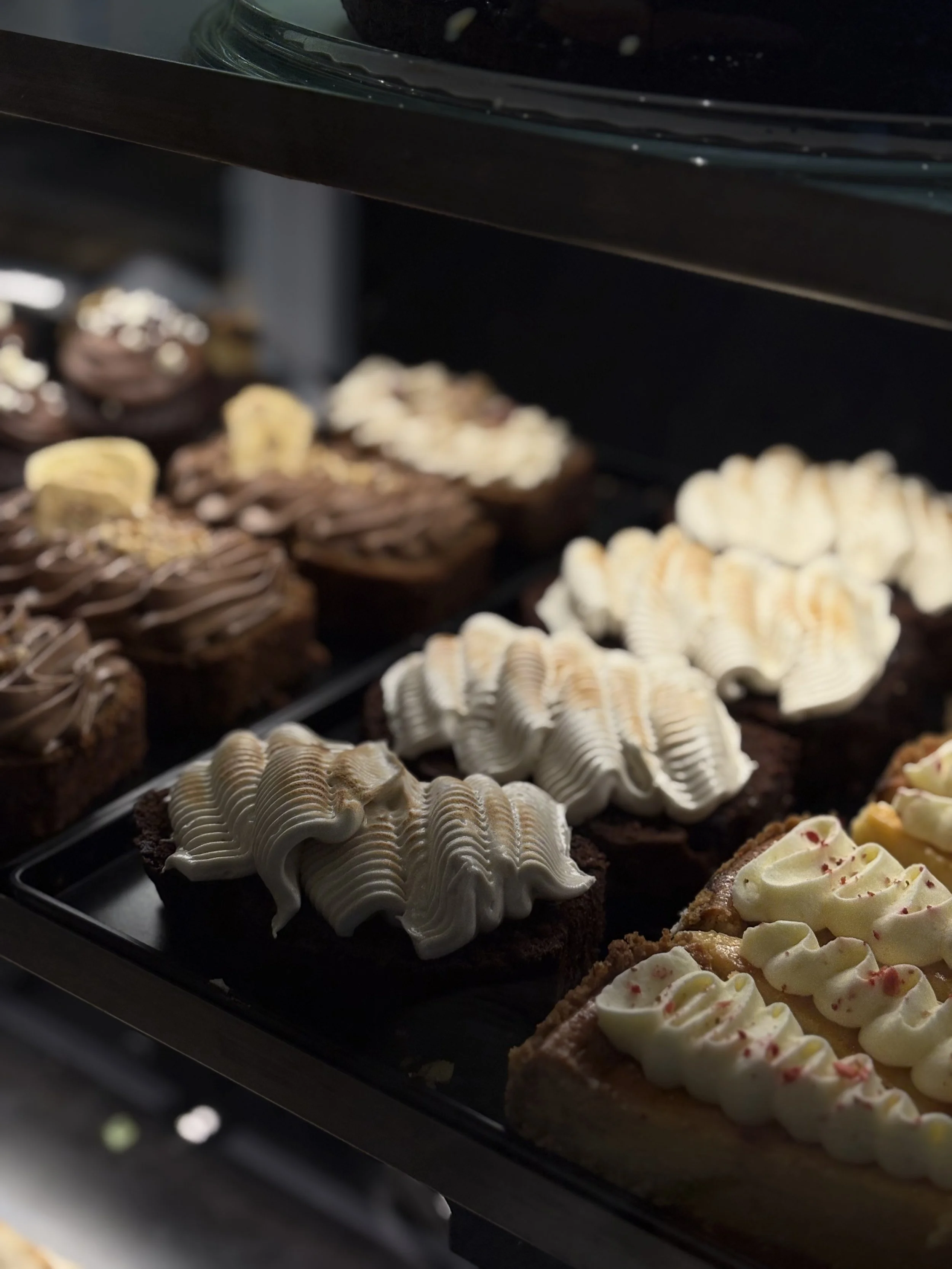 Erilaisia leivoksia, esim. kakkupaloja ja pikkuleipiä, esillä vitriinissä.