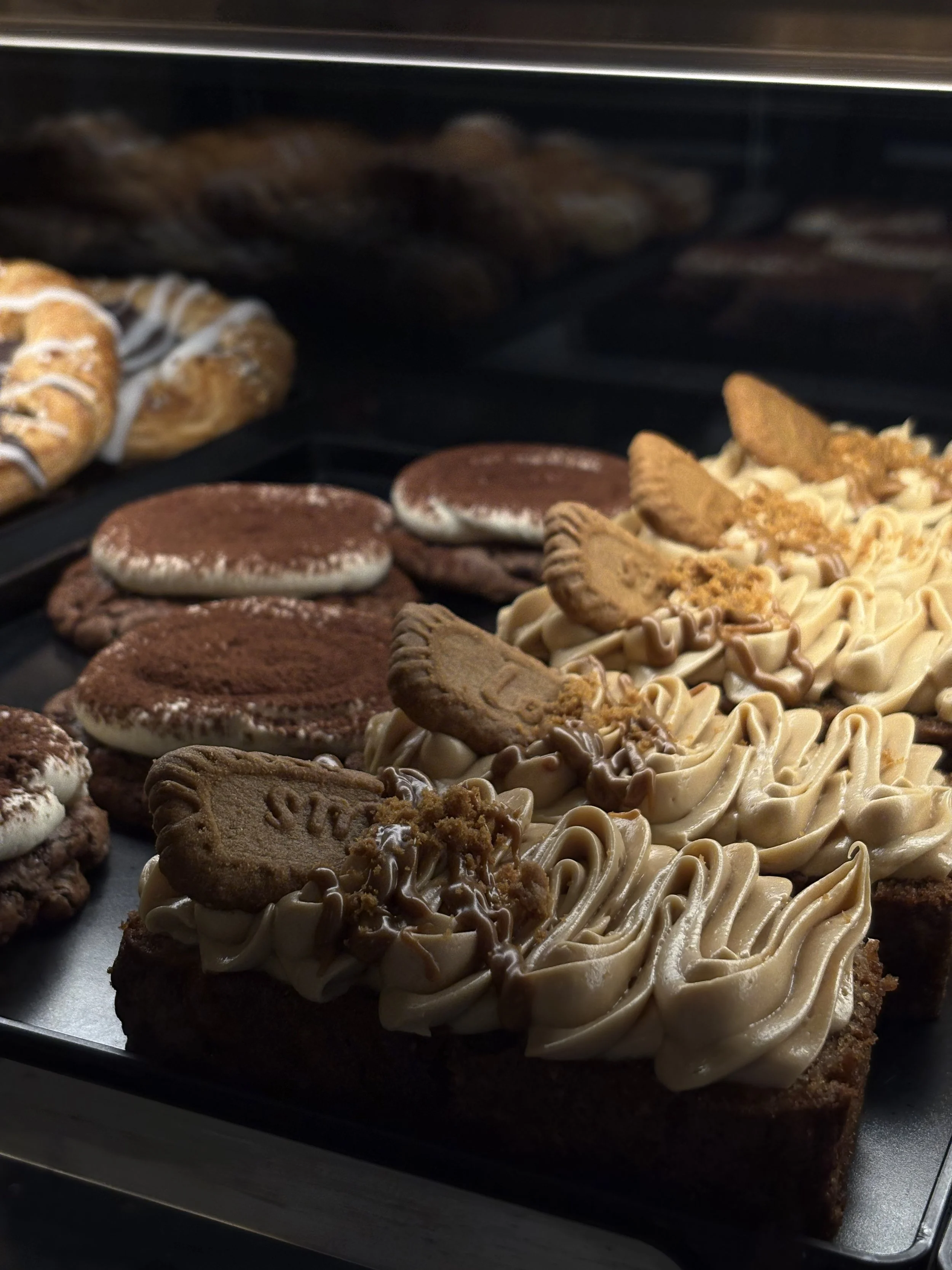 Leivoksia vitriinissä JAM Café & Barissa, Tiramisu keksejä ja omena-biscoff kakkuja.