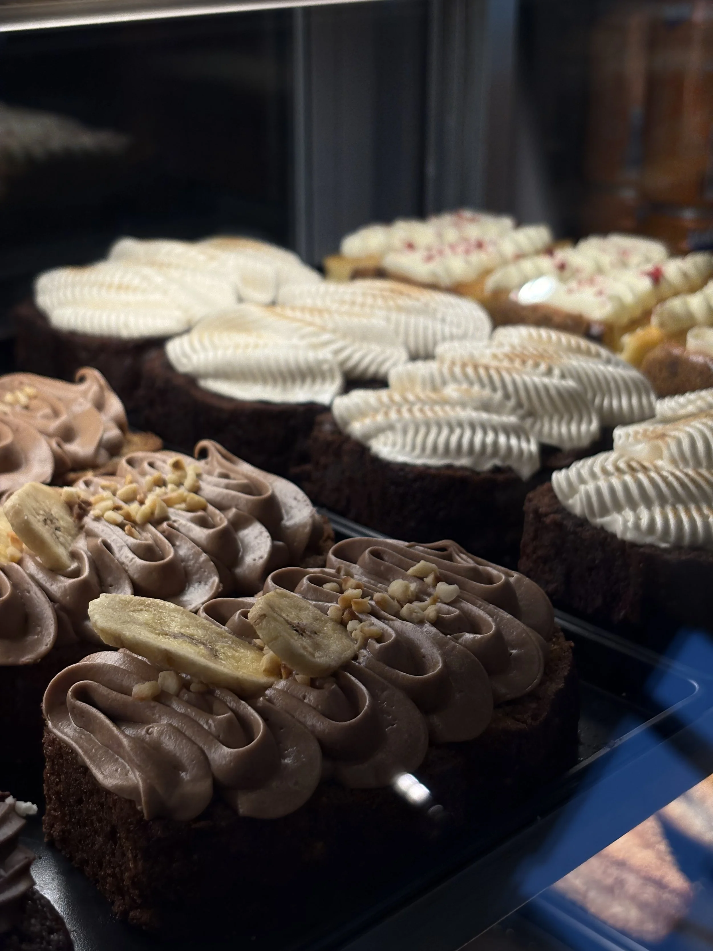 Runsaalla kuorrutteella olevia leivonnaisia, kuten kakkuja ja kääretorttuja JAM Café & Bar vitriinissä. 