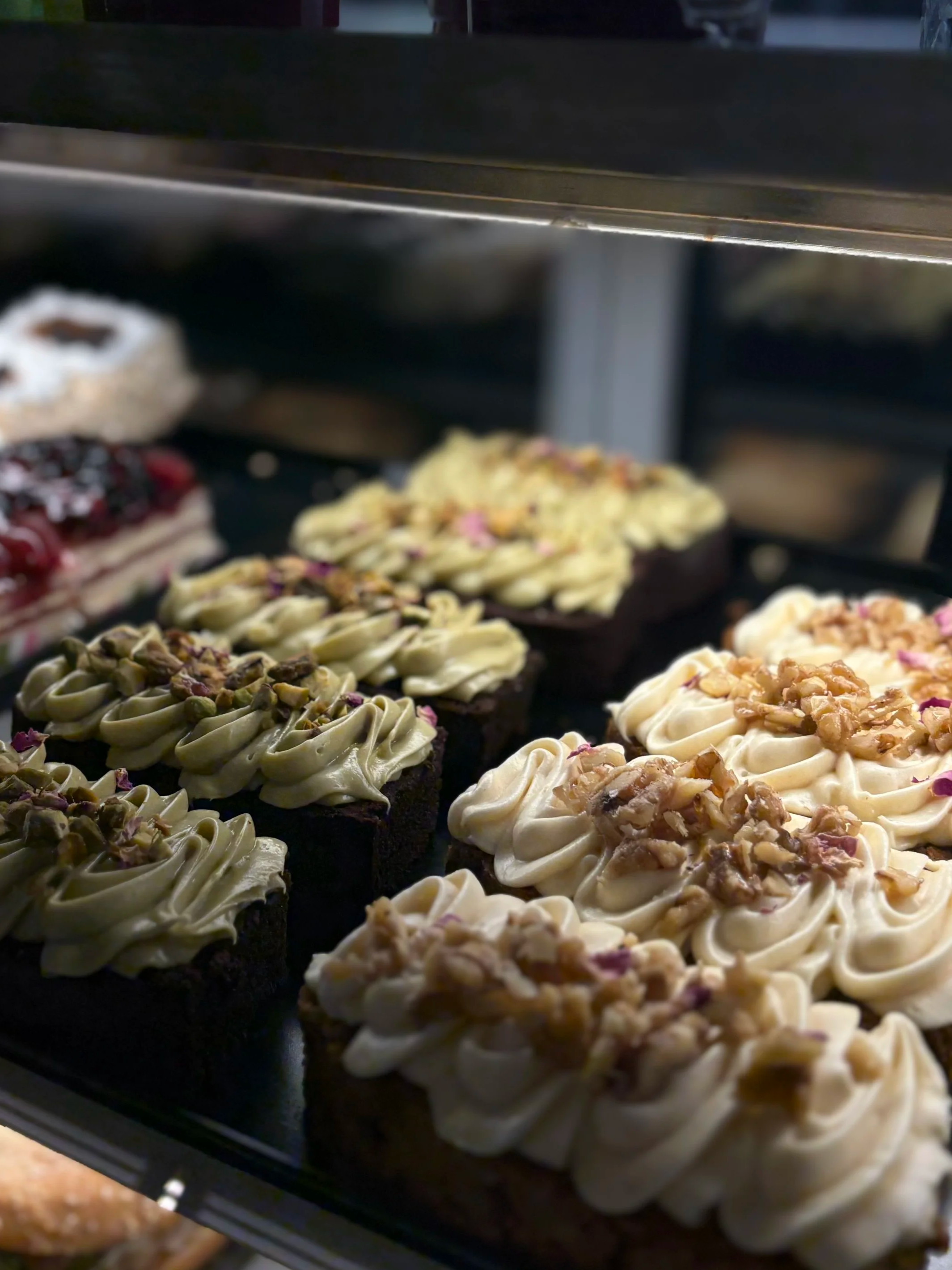 Leivonnaisia kakkuja ja muffineja näytillä vitriinissä.