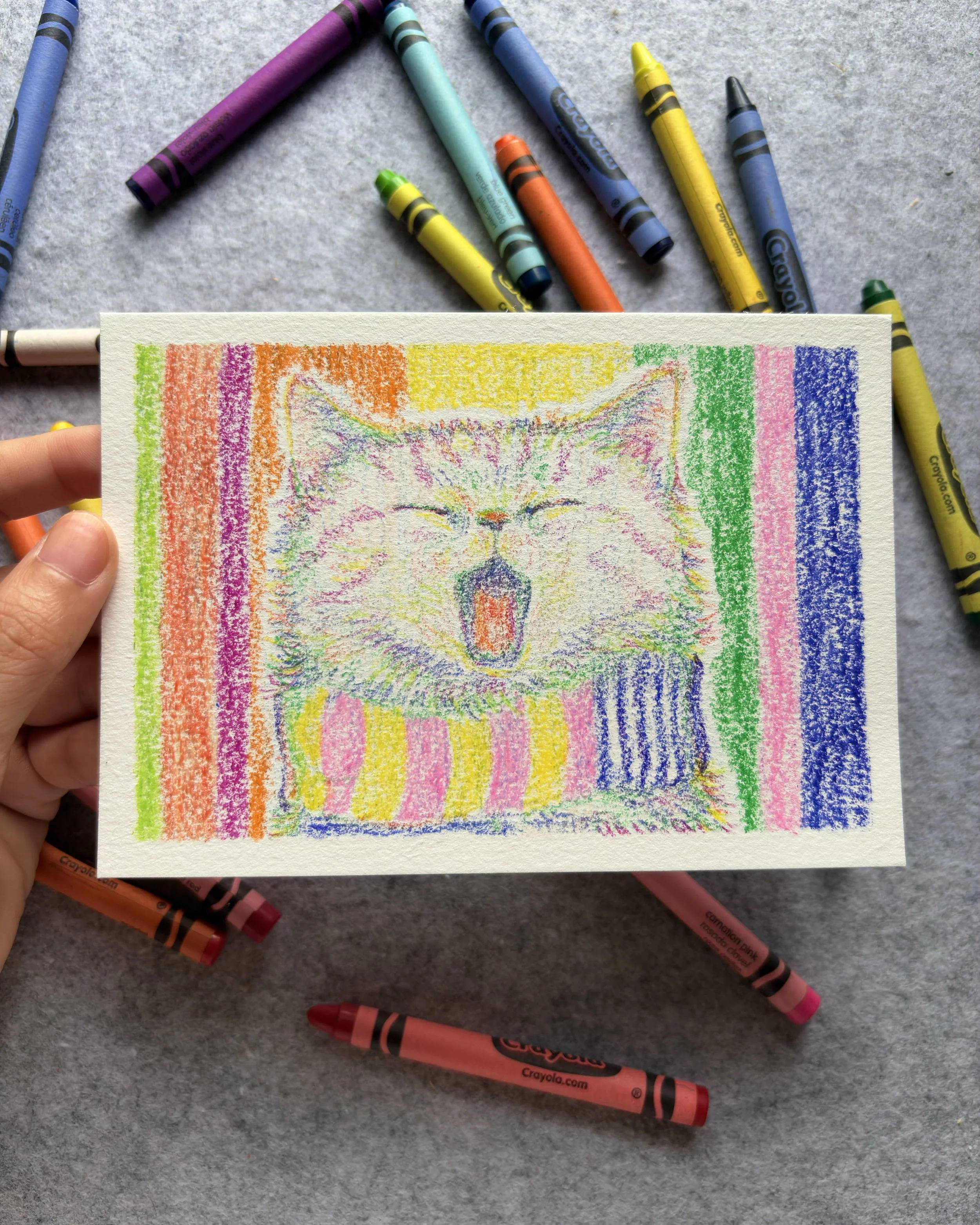 Drawing of a yawning animal, possibly a fox or wolf, created with colorful crayons on a small piece of paper.